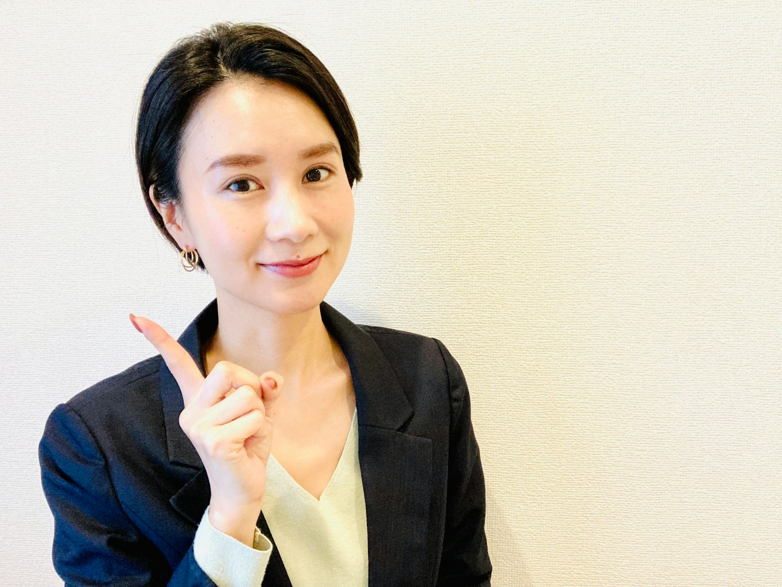 一位穿着商务套装的女性微笑着用手指指向