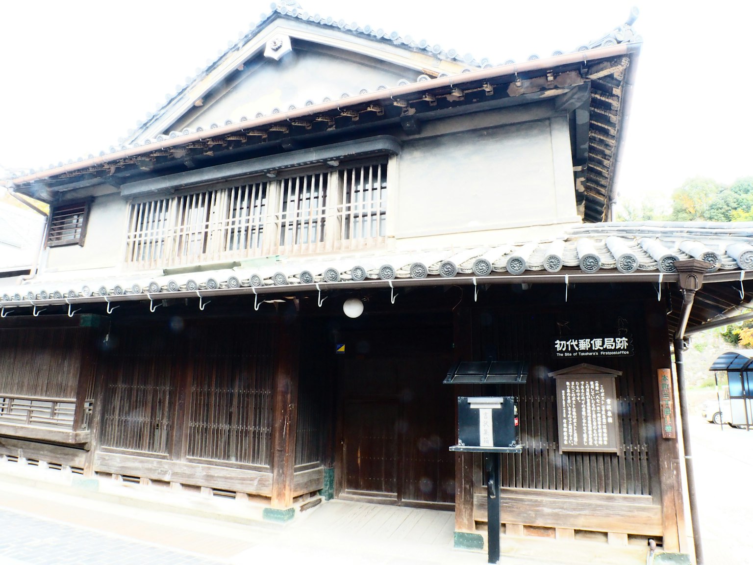 Eksterior rumah kayu tradisional Jepang dengan atap ubin tua dan jendela kisi kayu