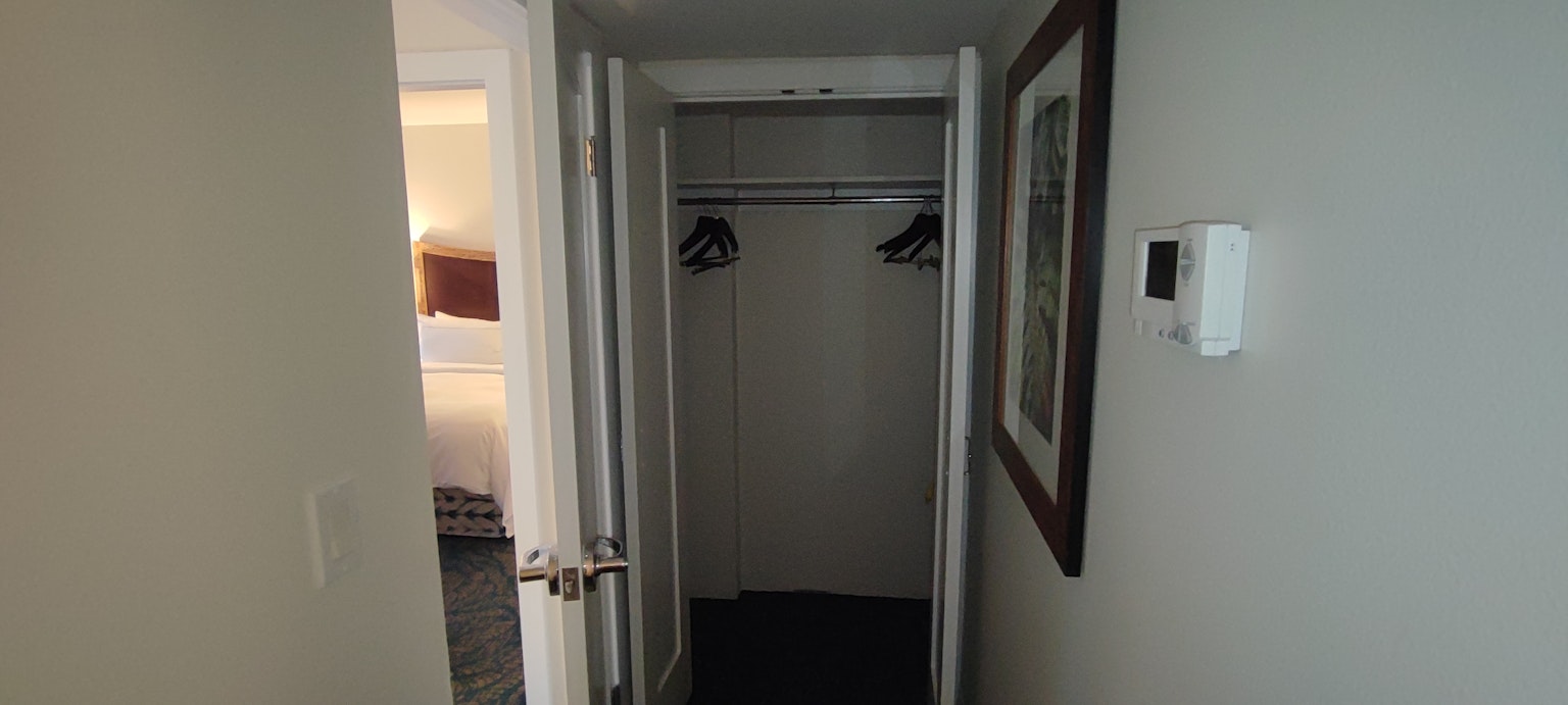 Entrada a una habitación de hotel mostrando un armario con perchas
