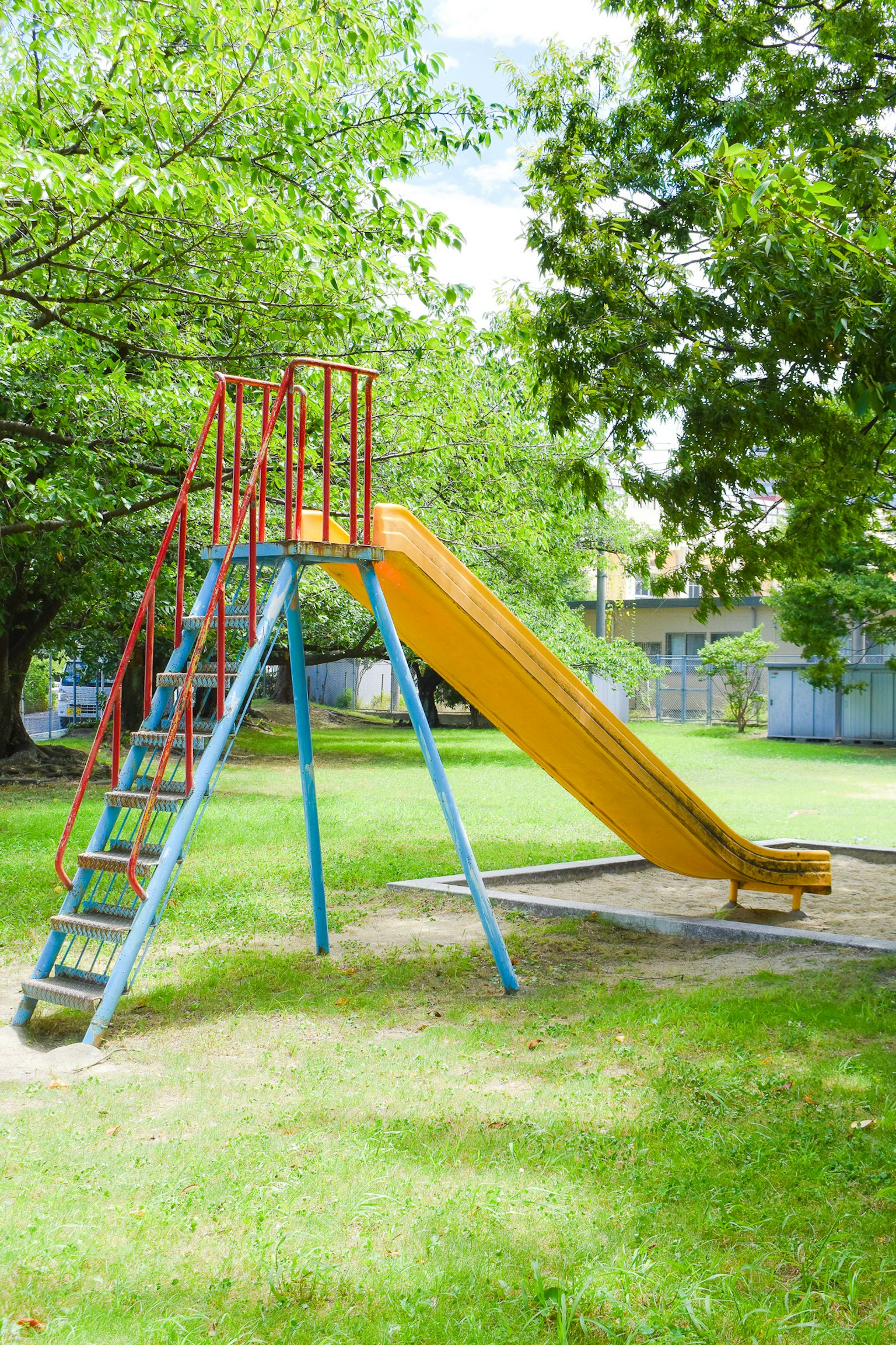 Toboggan coloré avec des escaliers dans un parc verdoyant