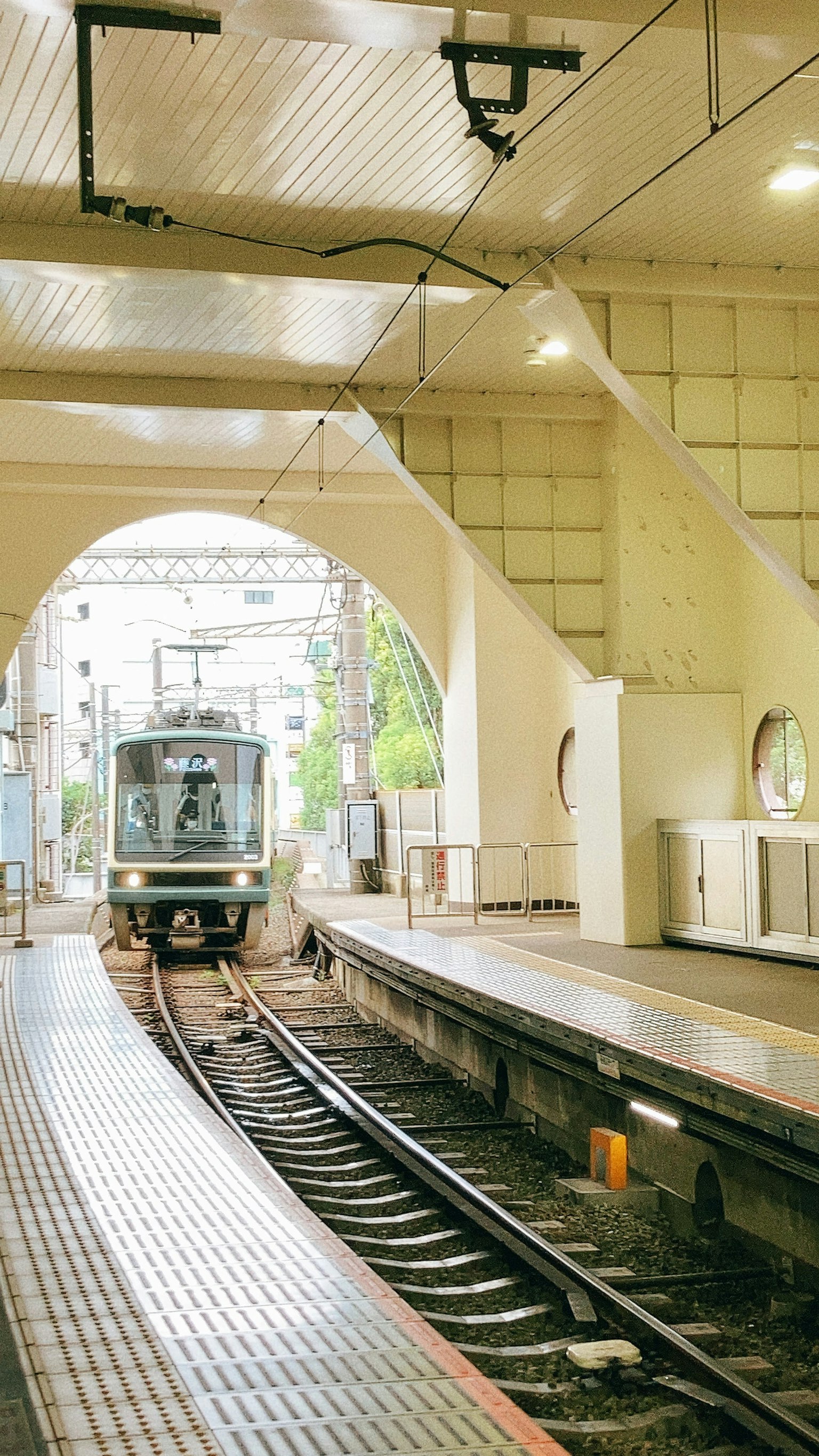 Train arriving at a bright station platform with white walls
