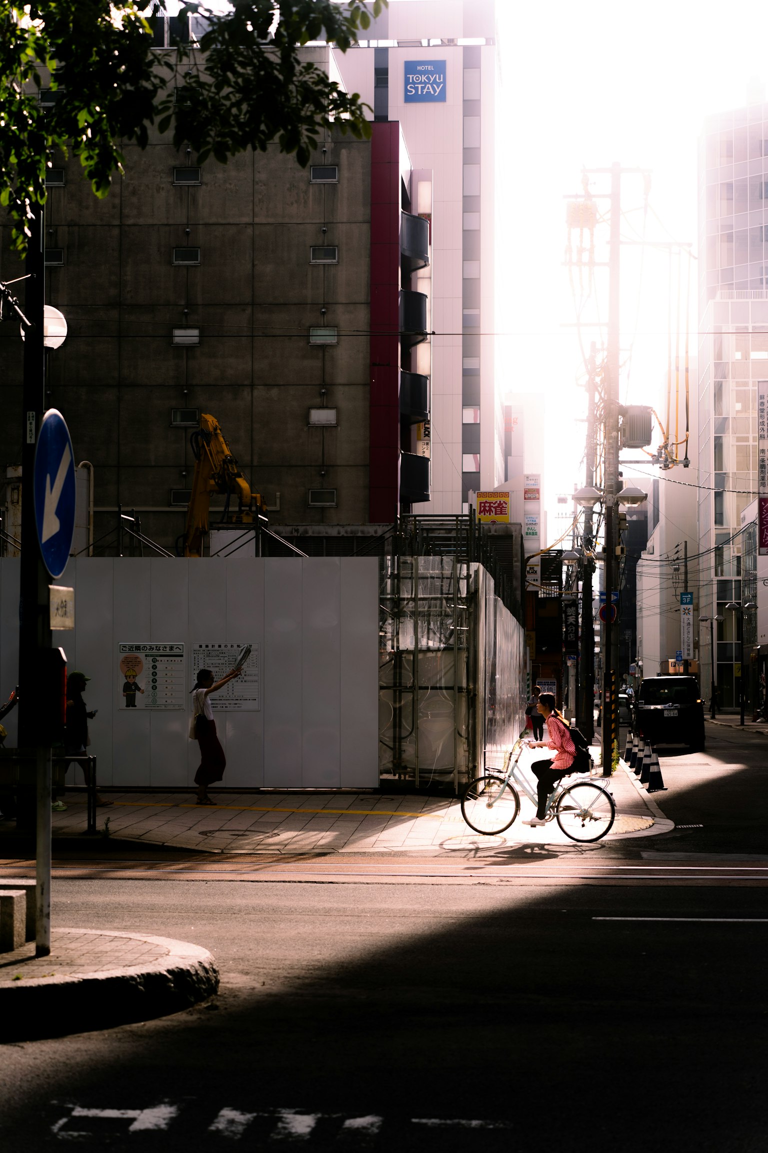 A cyclist on a bright street corner with a construction site in the background