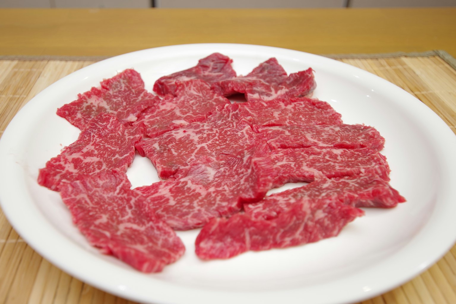 Thin slices of marbled beef arranged on a white plate