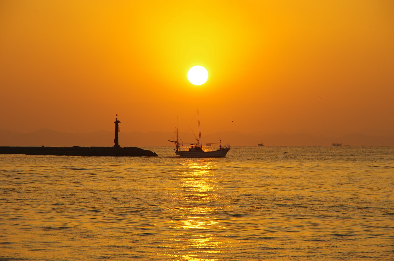 Ein schöner Sonnenuntergang über dem Ozean mit einem silhouettierten Leuchtturm und Schiff