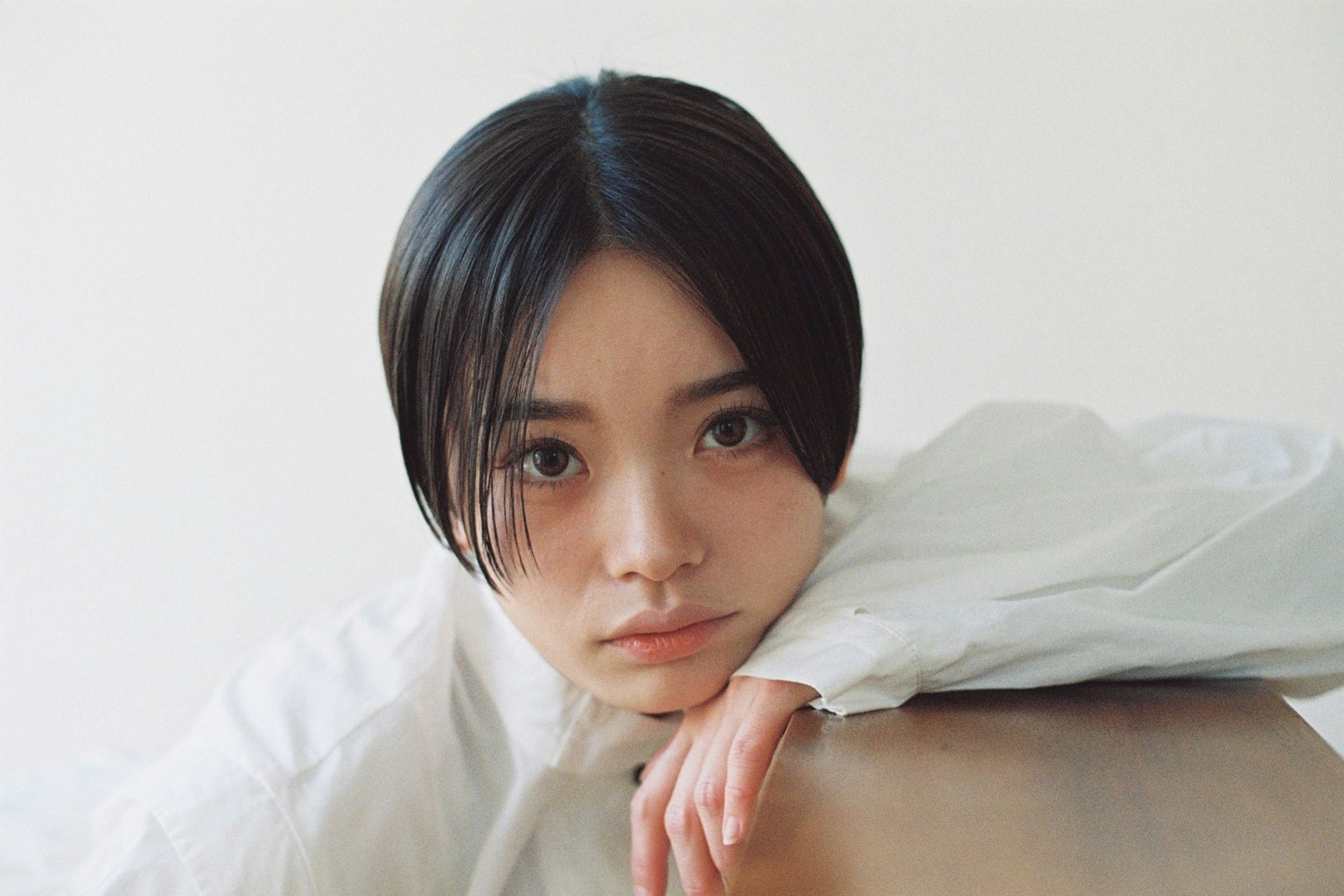 穿著白襯衫的年輕女性把手臂放在桌子上