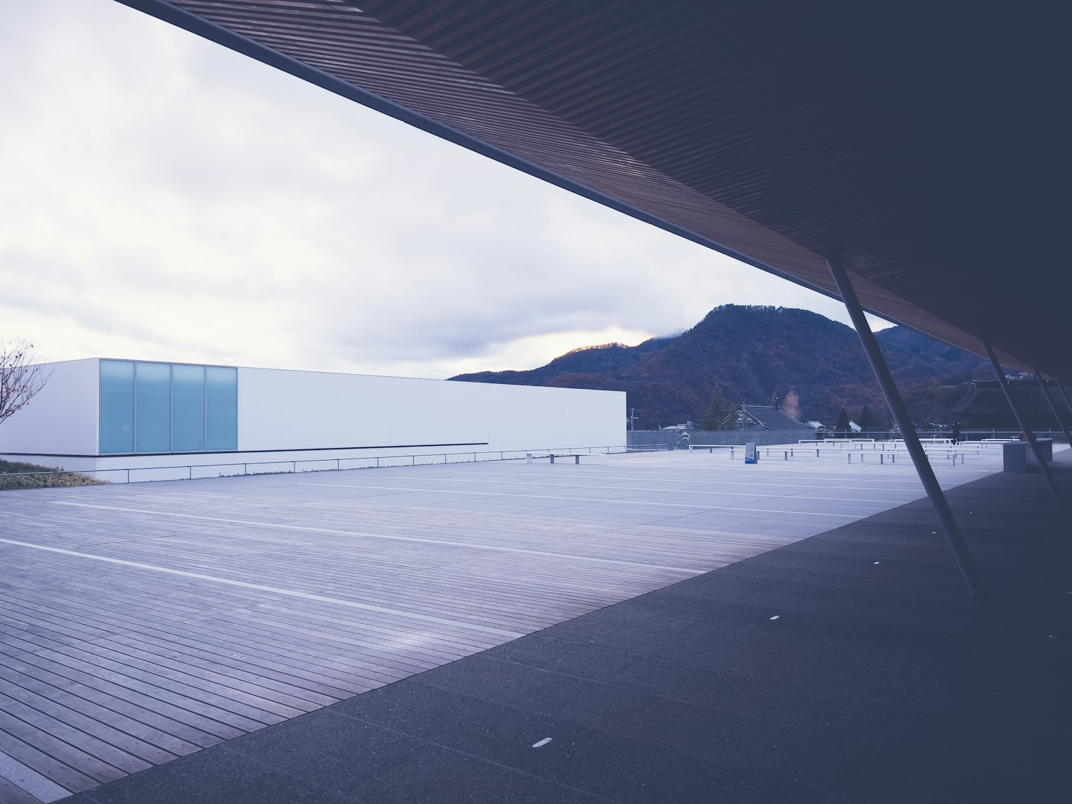 Edificio moderno con fondo montañoso y amplia terraza de madera