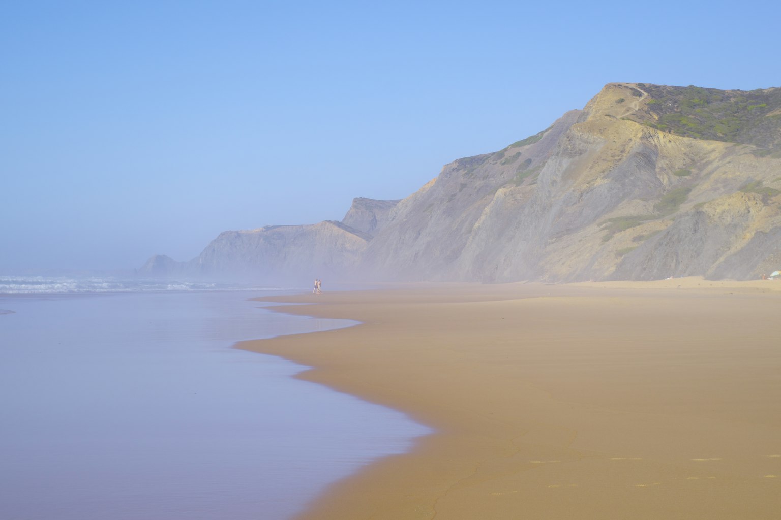 Scenic coastline with mist-covered cliffs and sandy beach