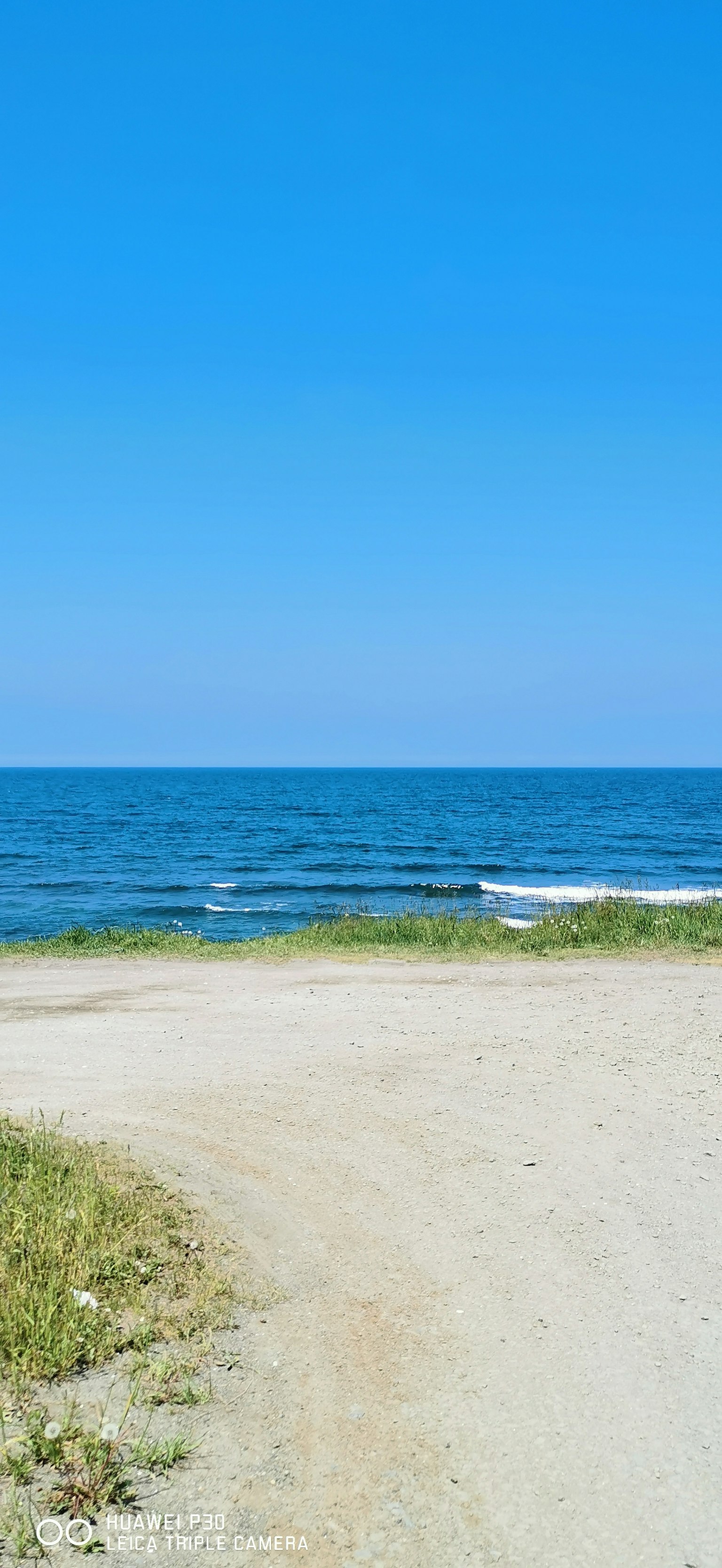 Vista panoramica di un cielo blu e dell'oceano con un sentiero sabbioso che conduce all'acqua