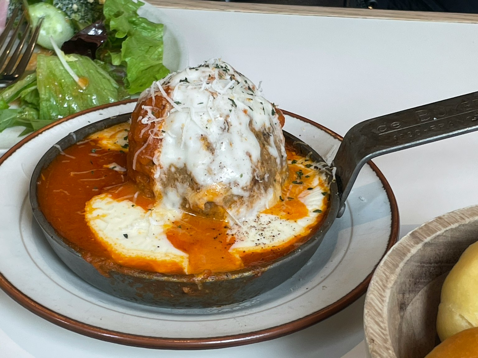 Bola daging disajikan dalam wajan dengan saus krim dan rempah