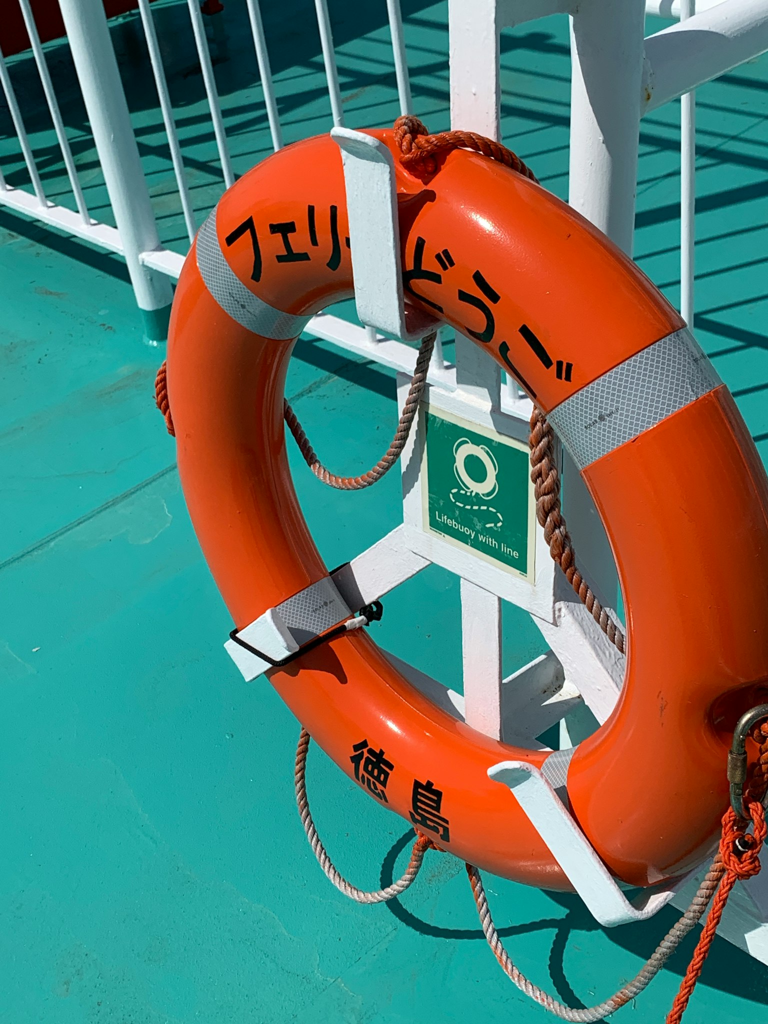 An orange lifesaver ring is placed on a ship's deck