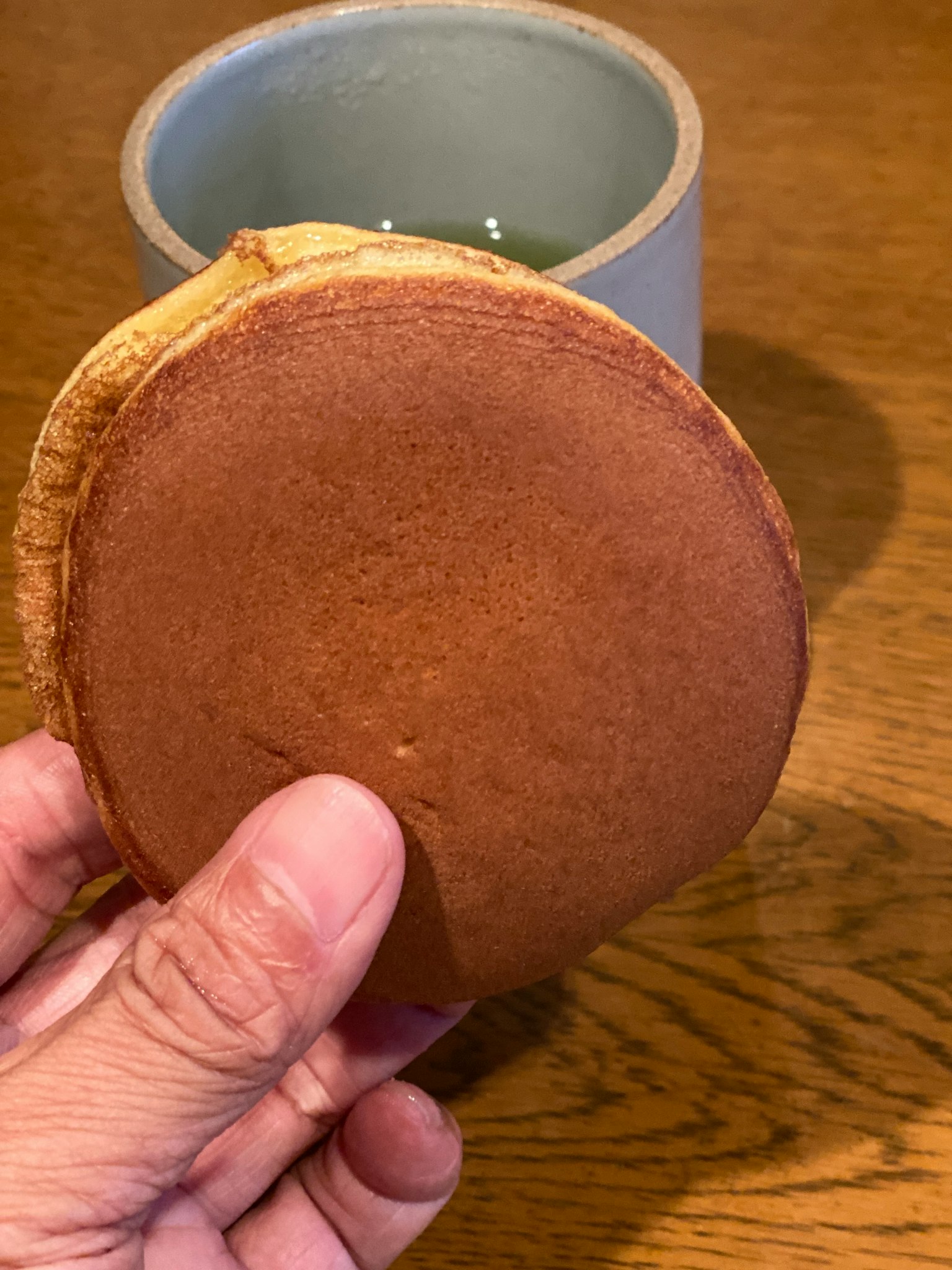 Dolce rotondo tenuto in mano con una tazza verde sullo sfondo