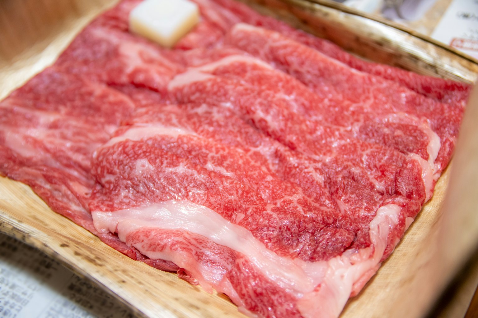 Hermosas rebanadas de carne de res Wagyu con un hermoso veteado presentadas en una bandeja de madera
