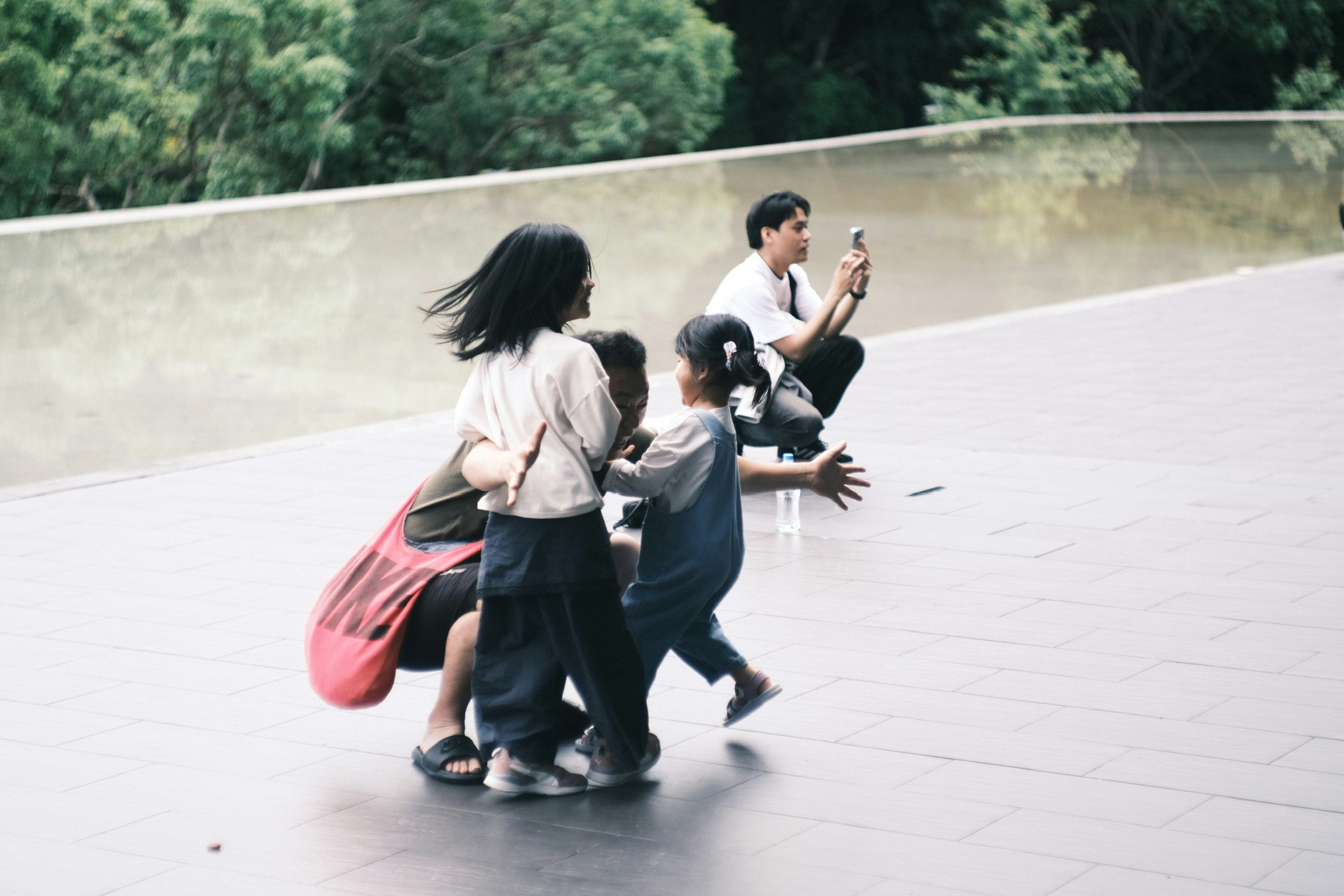 Kinder rennen und spielen auf einem Platz mit einigen Erwachsenen im Hintergrund