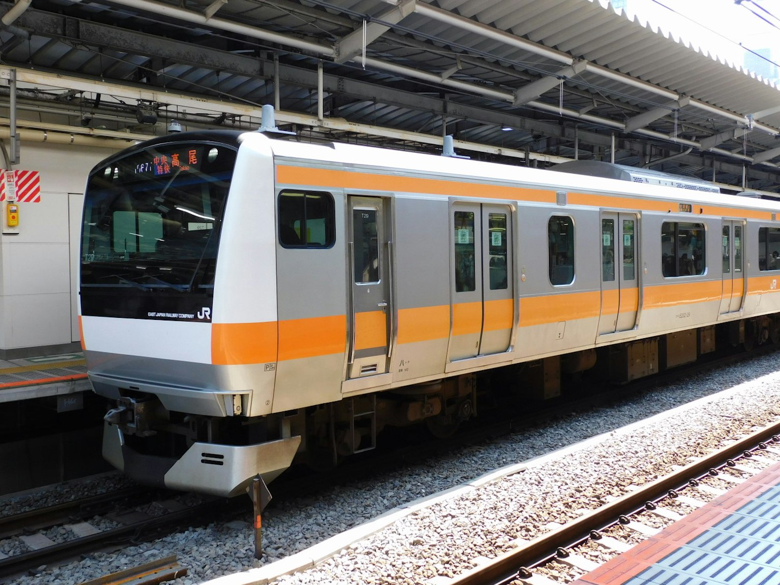 一列帶有獨特橙色條紋的火車停靠在車站