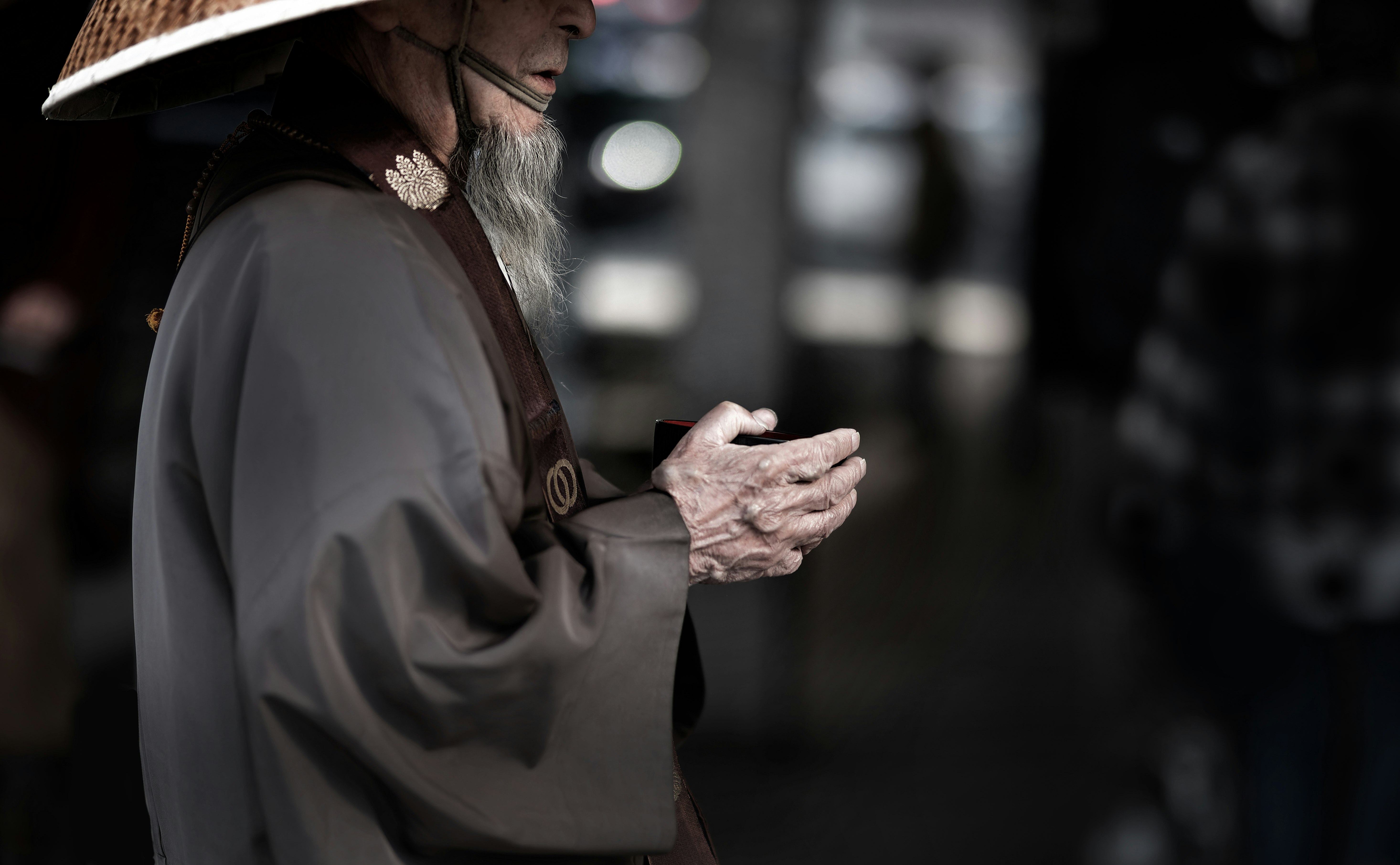 雨の路地で手を合わせる帽子の男性