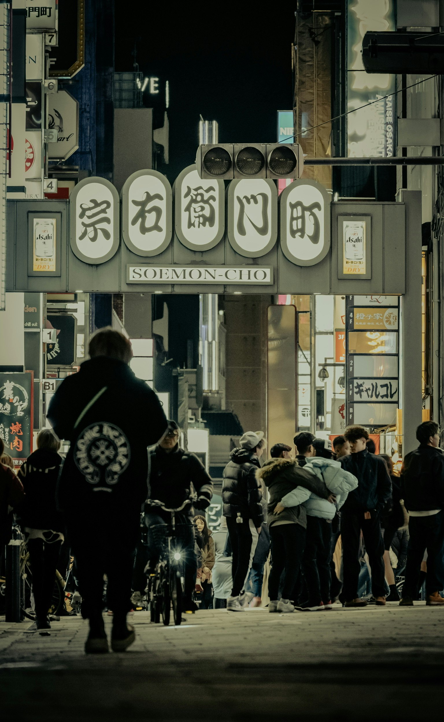 Đám đông người đi bộ trên một con phố sôi động với biển hiệu sáng đèn vào ban đêm