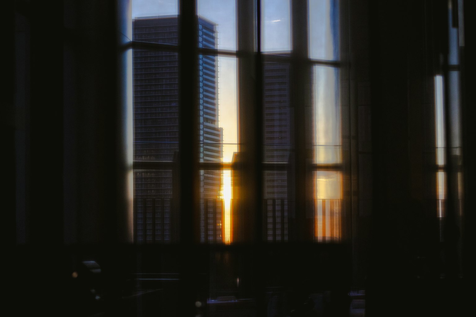 Vista del atardecer a través de las ventanas de un edificio urbano con reflejos