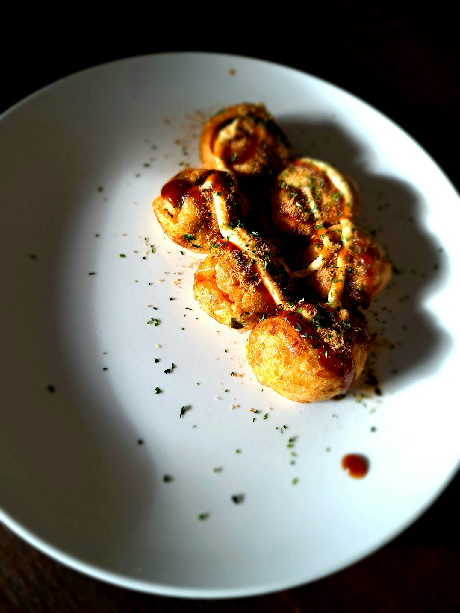 Takoyaki ngon được phục vụ trên đĩa trắng với topping và sốt