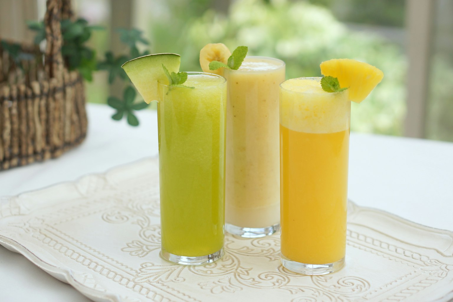 Cocktails rafraîchissants de couleurs verte, crème et orange disposés sur une table