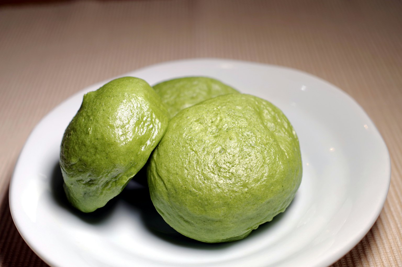 Bollos verdes al vapor dispuestos en un plato blanco