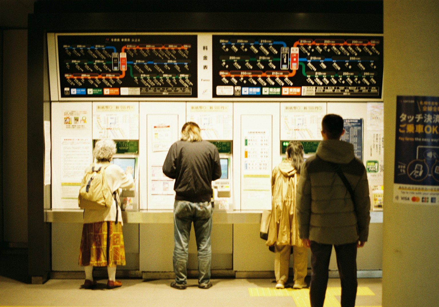 駅の券売機で切符を購入する人々の様子