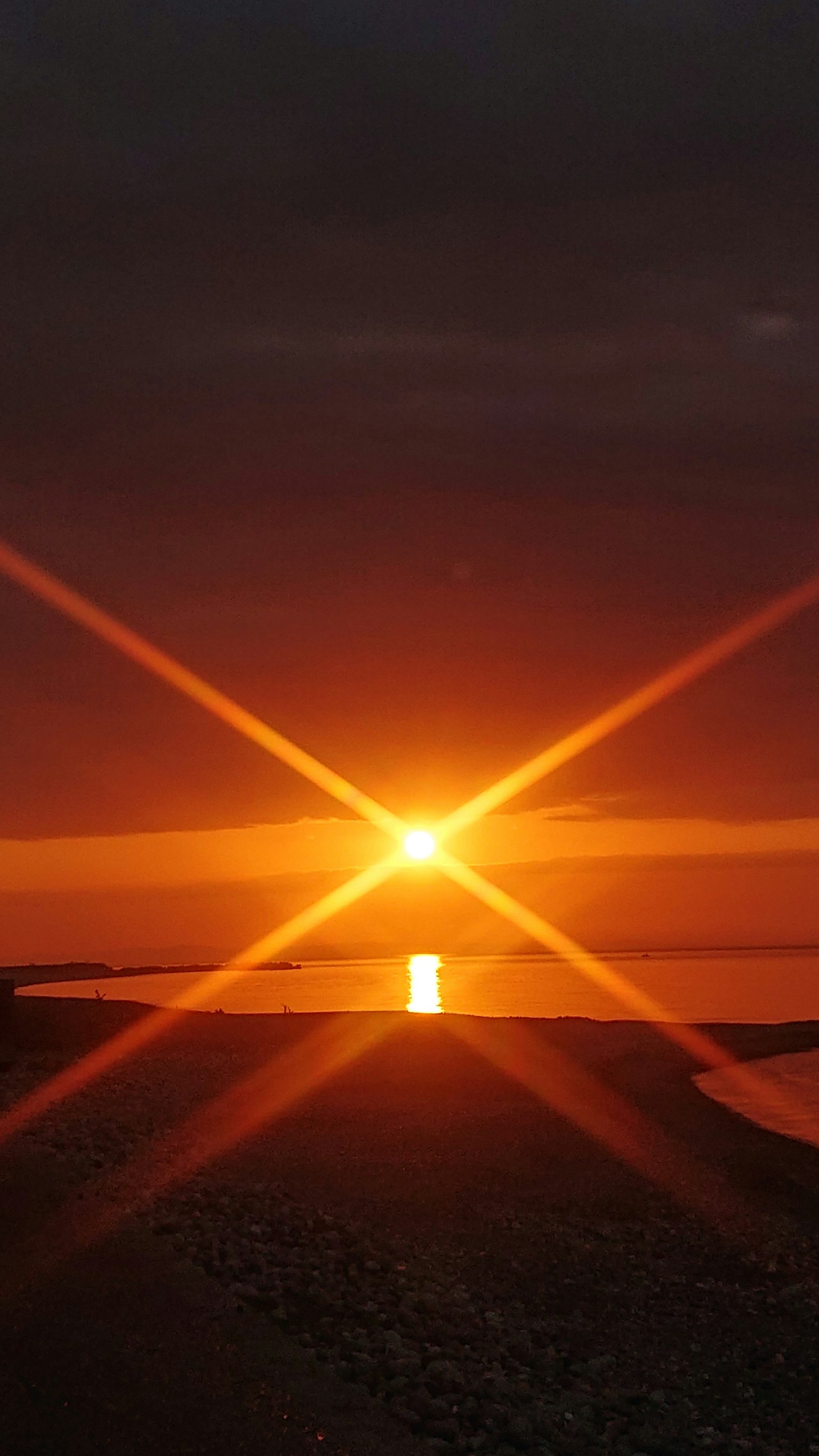 Coucher de soleil sur l'océan avec des reflets lumineux en forme d'étoile
