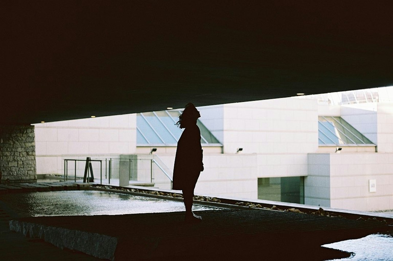 Silhouette d'une personne se tenant dans l'ombre avec un bâtiment moderne en arrière-plan