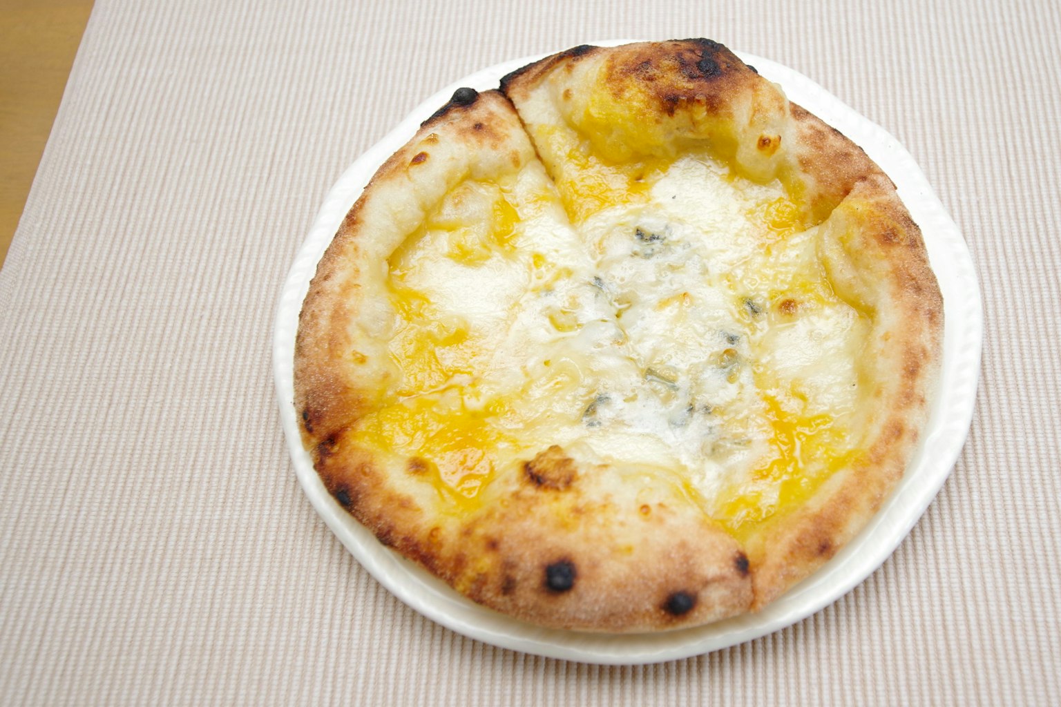 Pizza Napoli phủ phô mai trên đĩa trắng