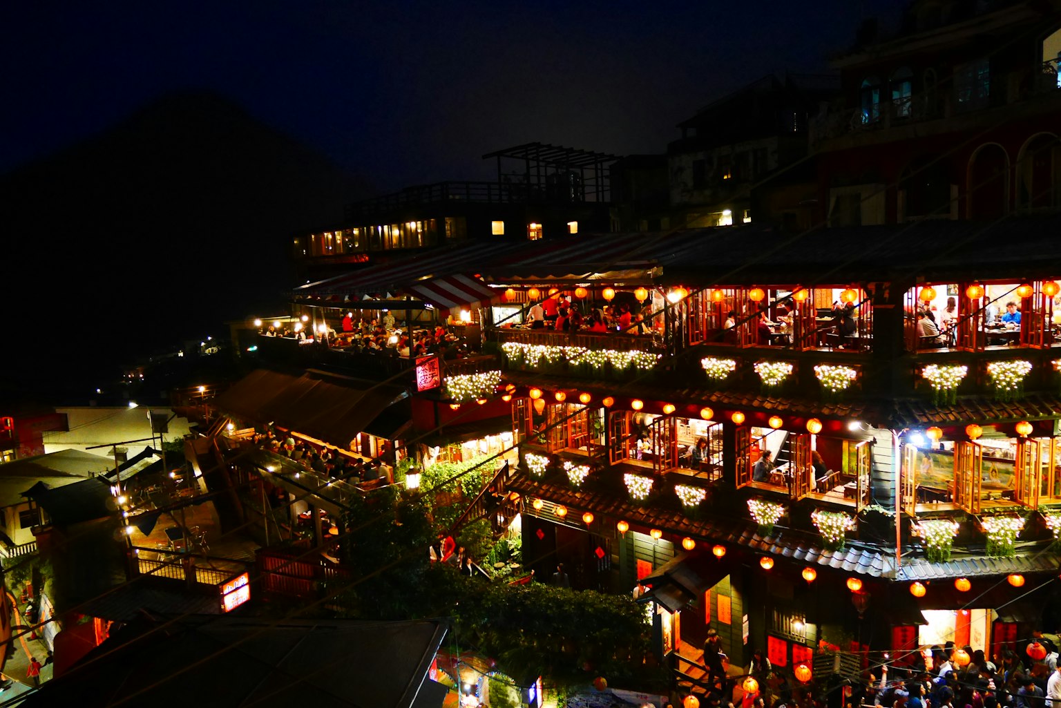Nachtansicht des Dorfes Jiufen mit beleuchteten Geschäften und Laternen