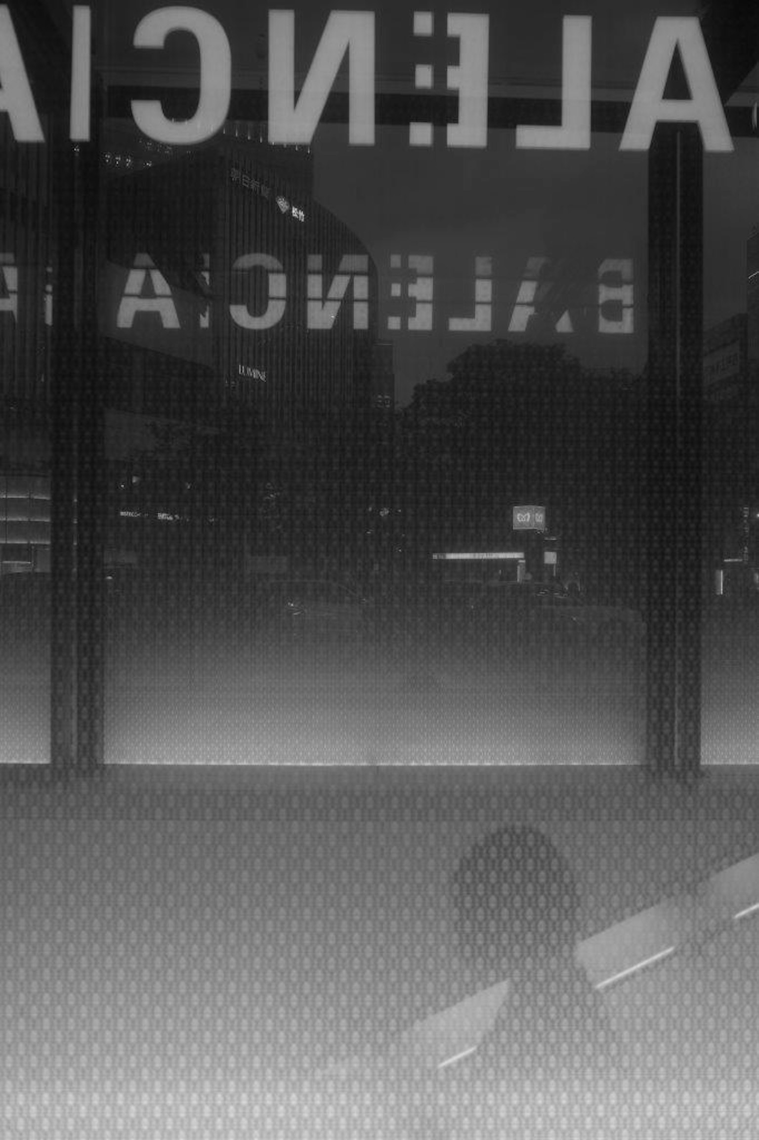 Riflesso di un paesaggio urbano notturno in una finestra che mostra Balenciaga