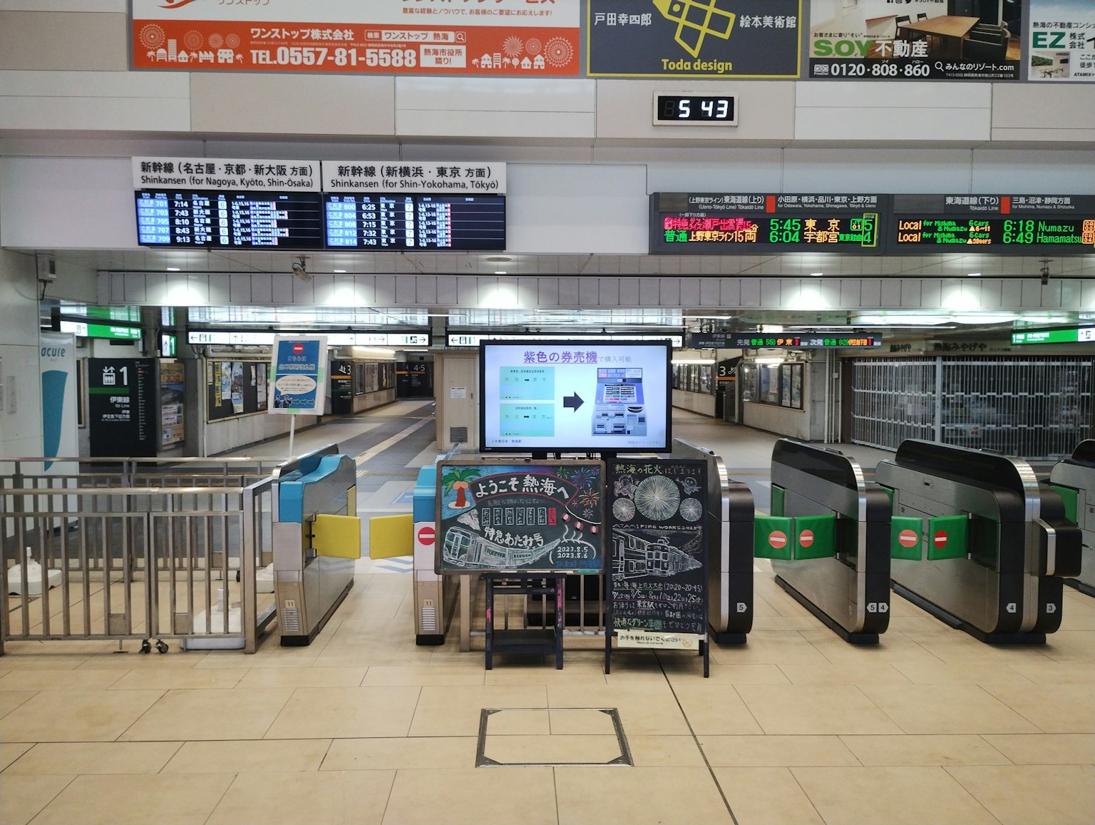 Empty train station platform with ticket barriers and digital display board