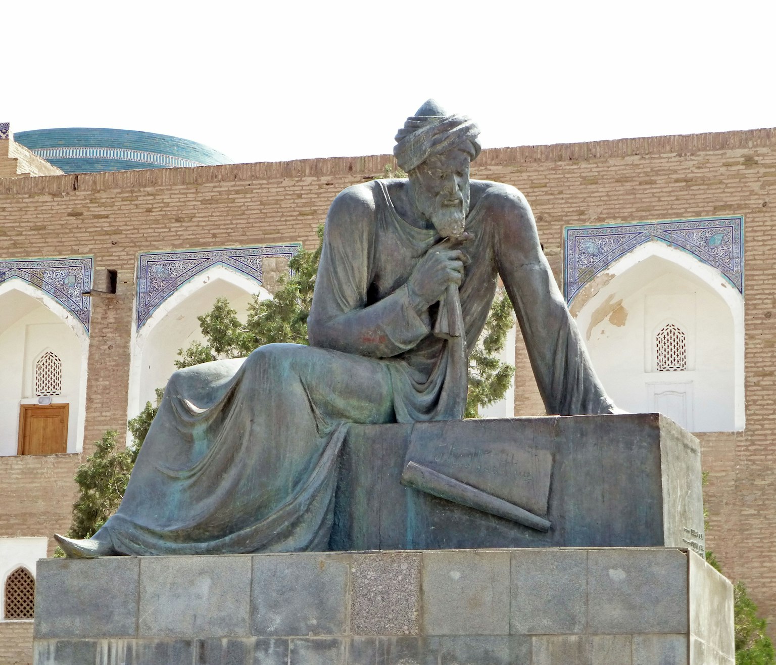 Statua in bronzo di una figura seduta che tiene un documento in una posa pensierosa