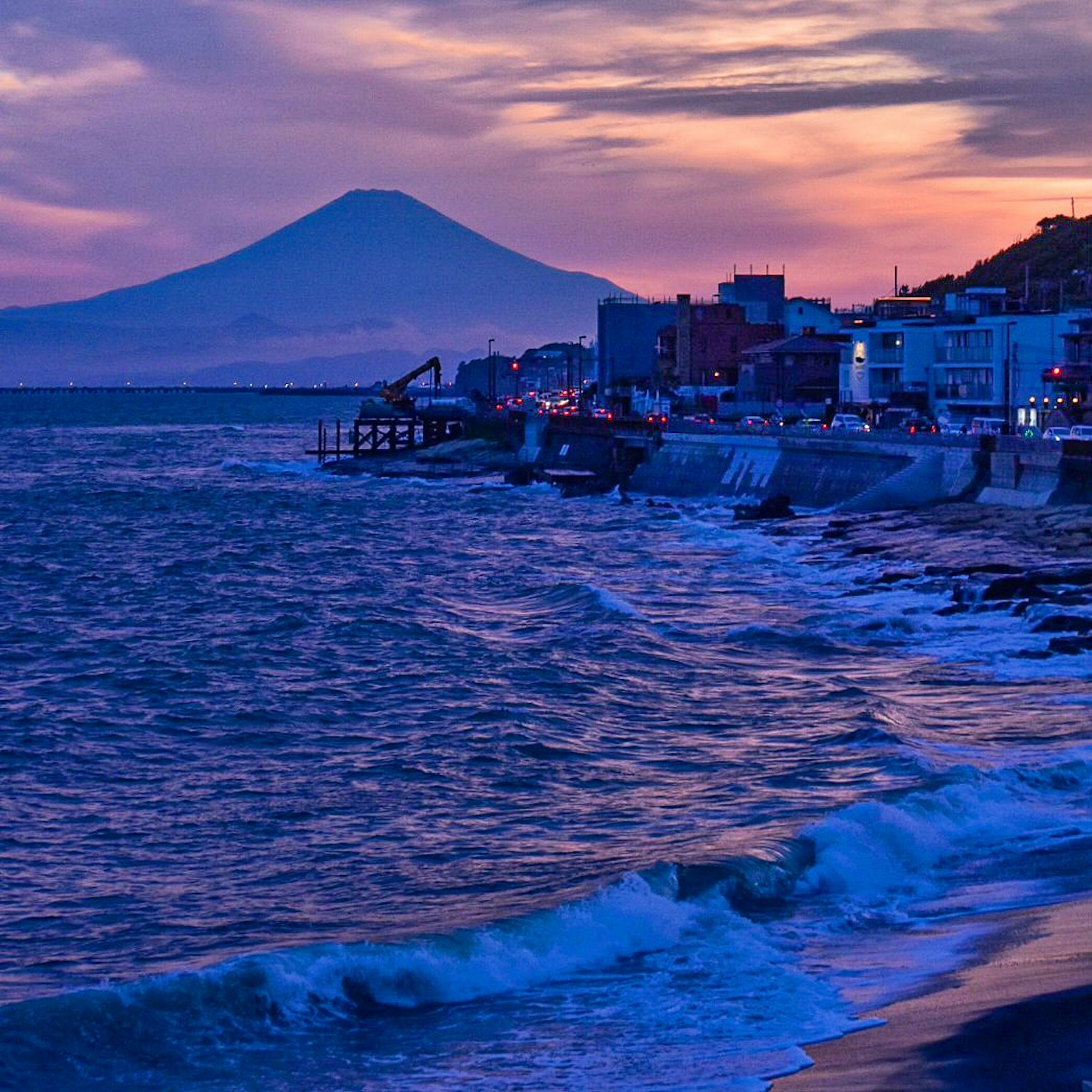 Vista costiera con il monte Fuji sullo sfondo cielo al tramonto e onde