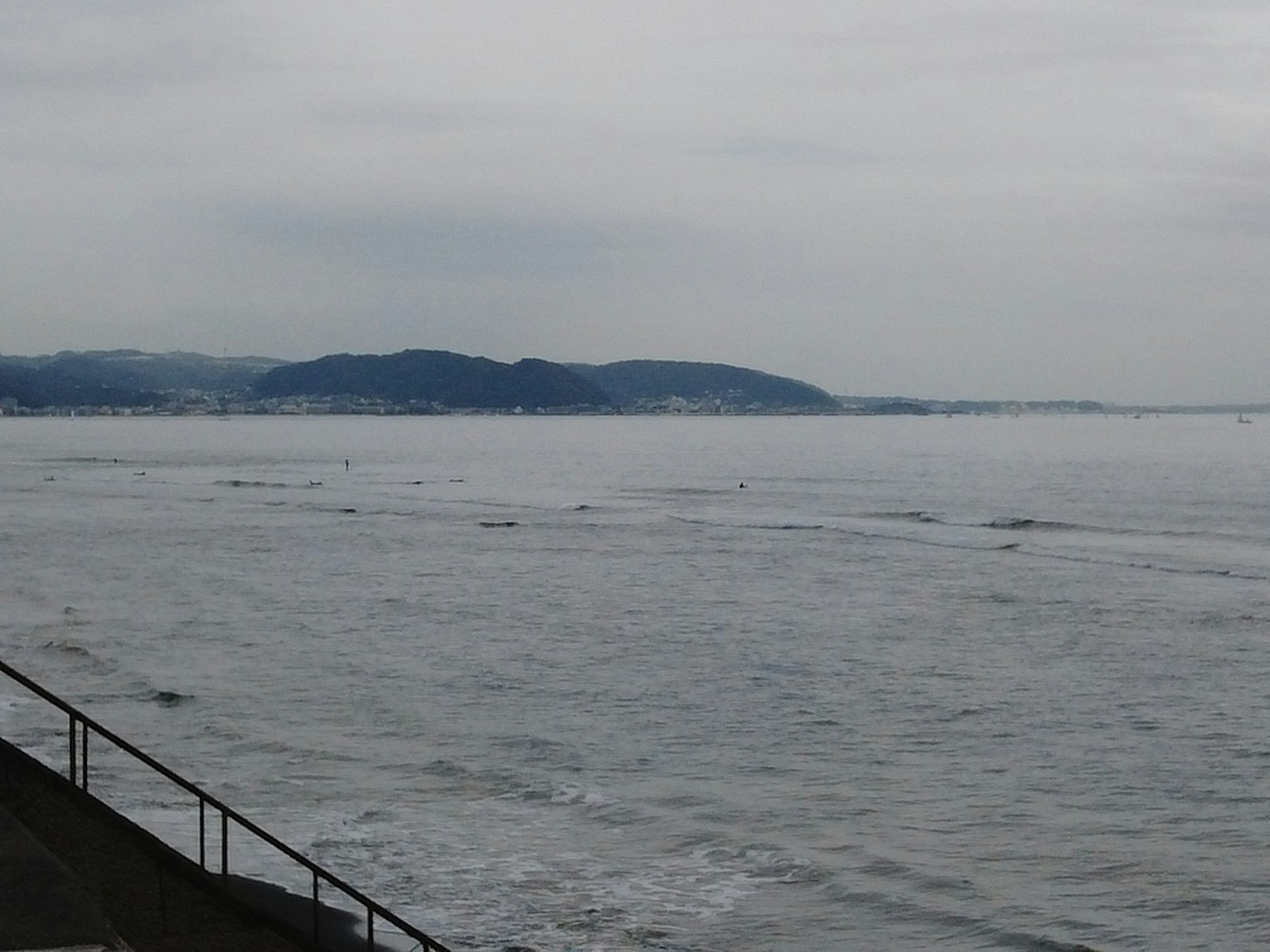Calm sea and cloudy sky landscape with mountains along the coast reflecting on the tranquil water surface