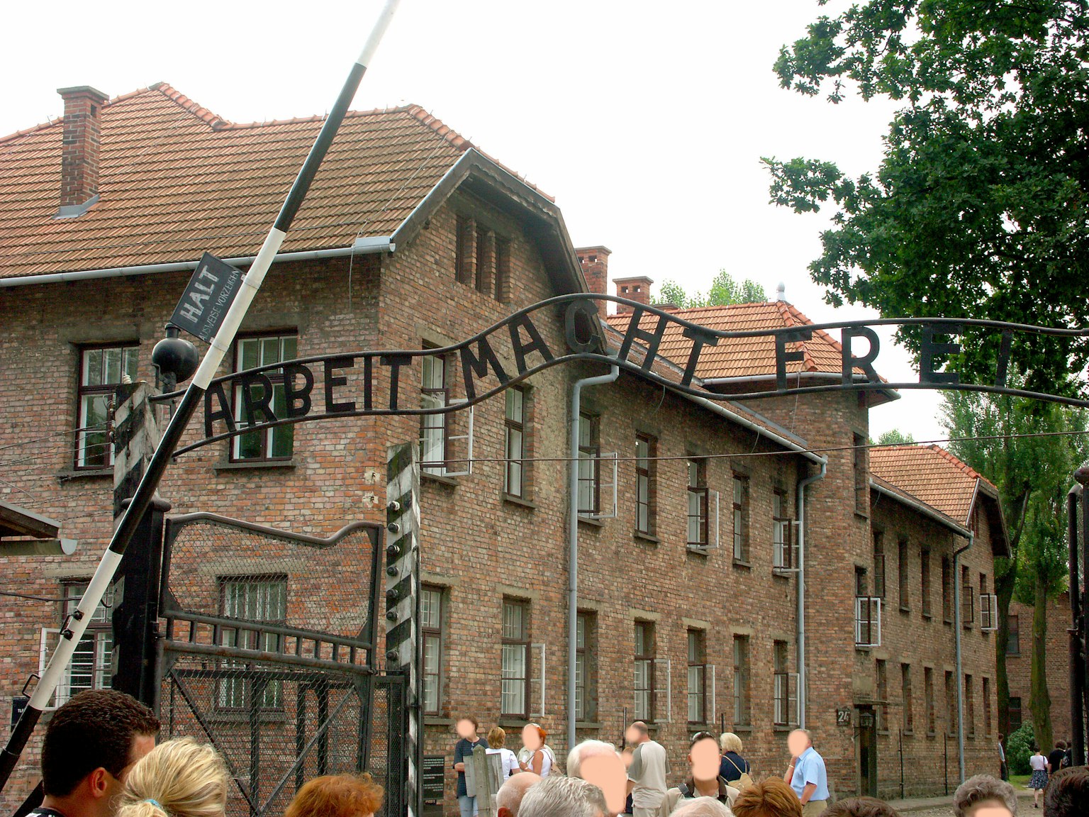 Cổng vào Auschwitz với biển hiệu Arbeit Macht Frei và các tòa nhà xung quanh