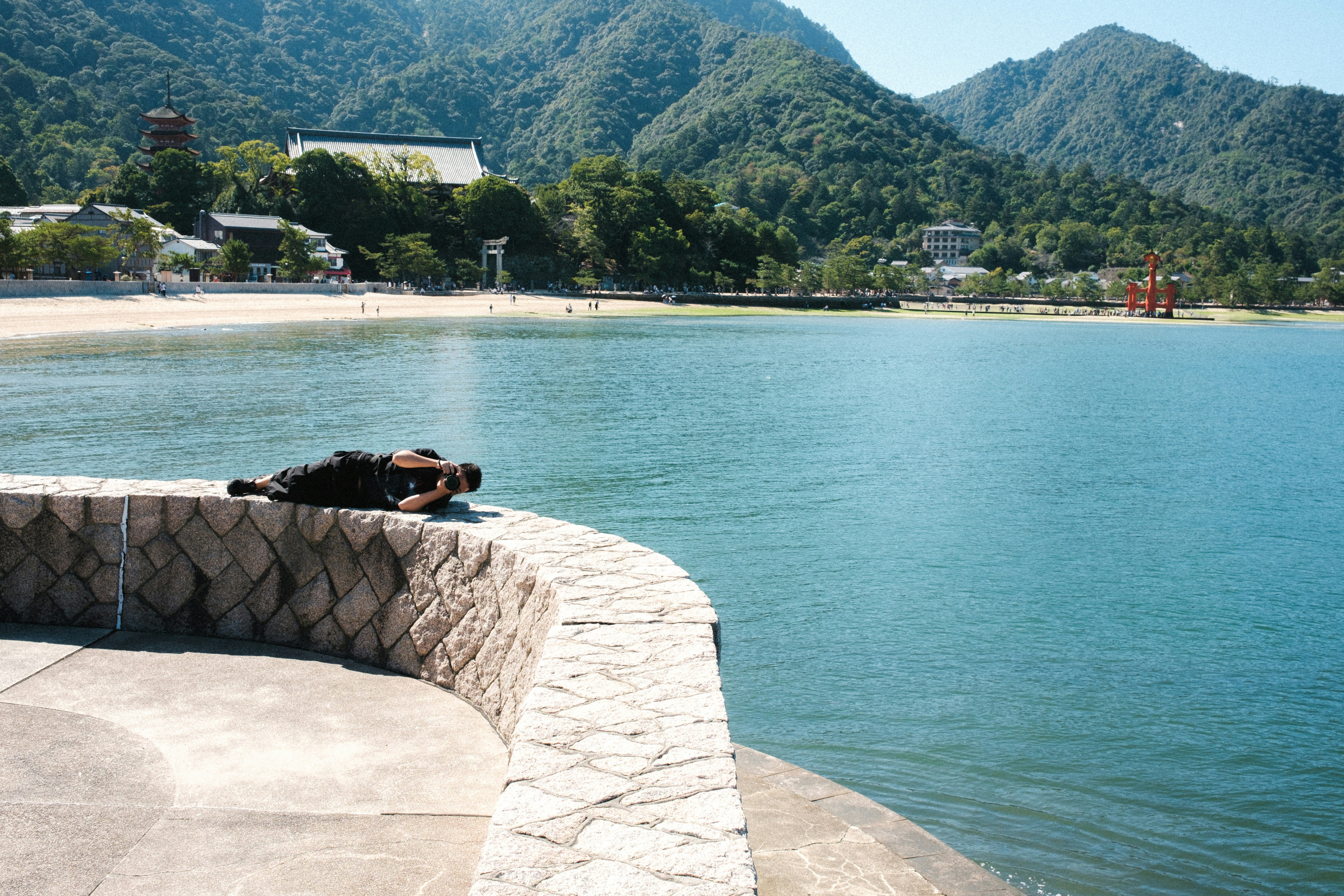湖畔の遊歩道で海辺のように撮影する人と山並みの景色