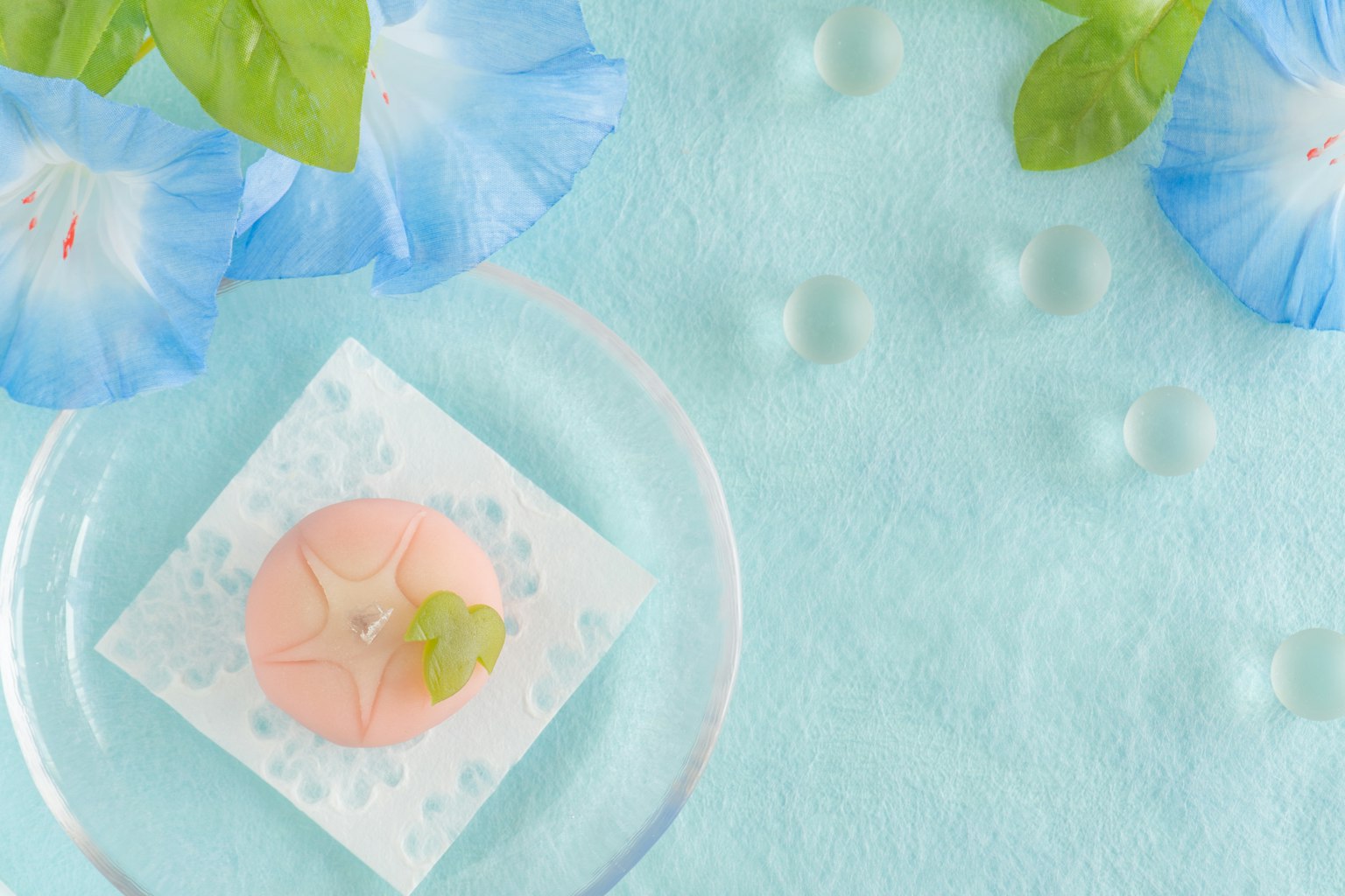 Eine schöne Stillleben mit einer rosa japanischen Süßigkeit und blauen Blumen vor einem hellblauen Hintergrund