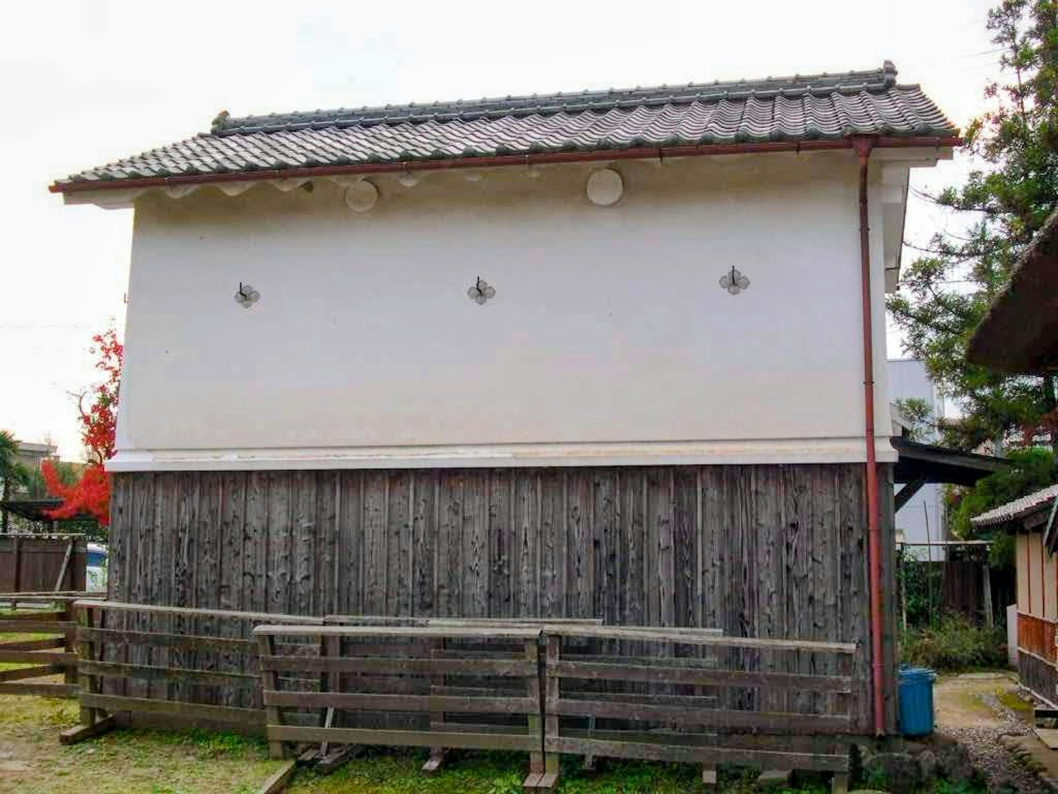 Vue latérale d'un bâtiment traditionnel japonais avec un mur blanc et une base en bois