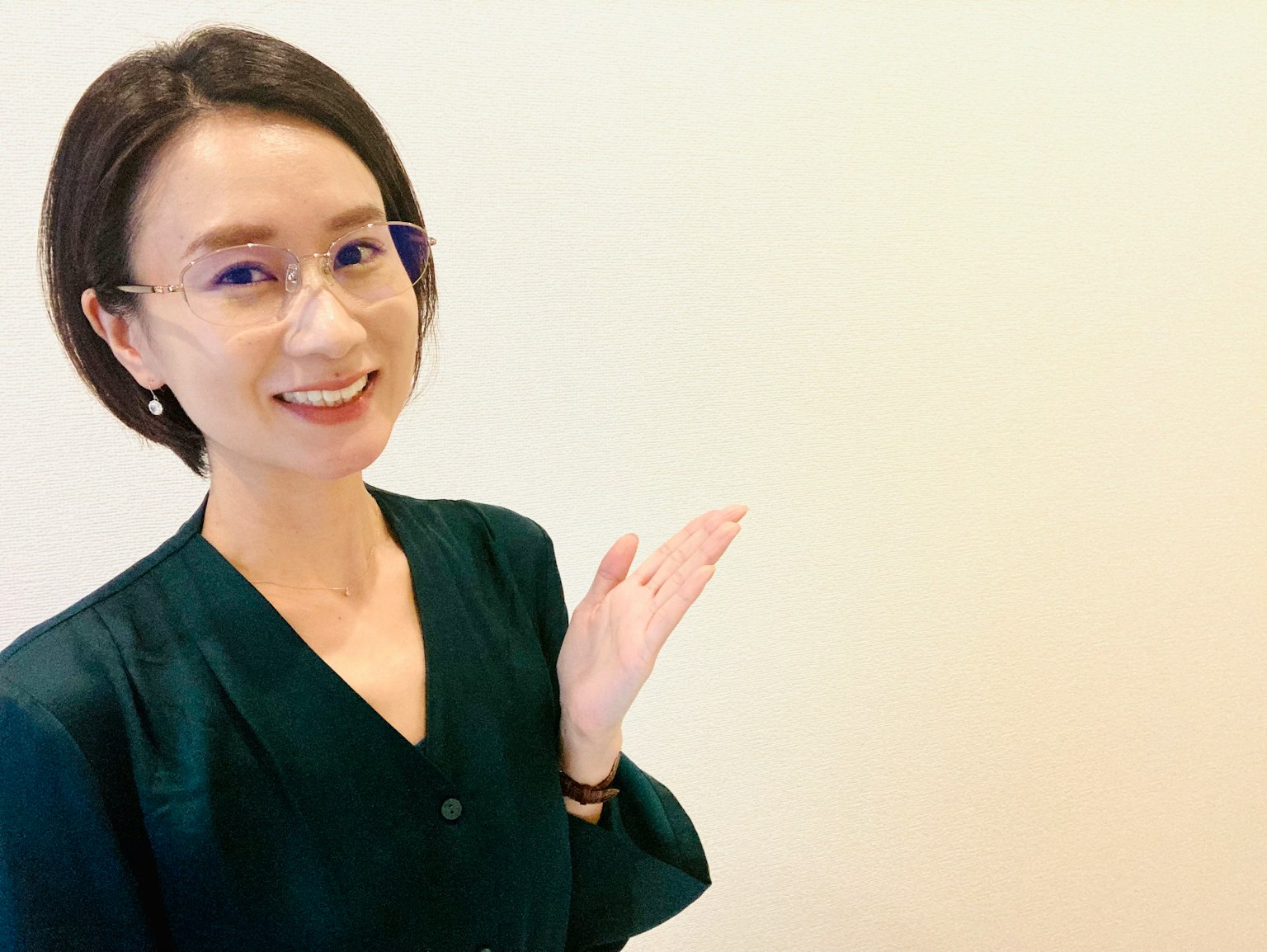 一名穿著黑色外套的女性微笑著，白色背景中伸出手