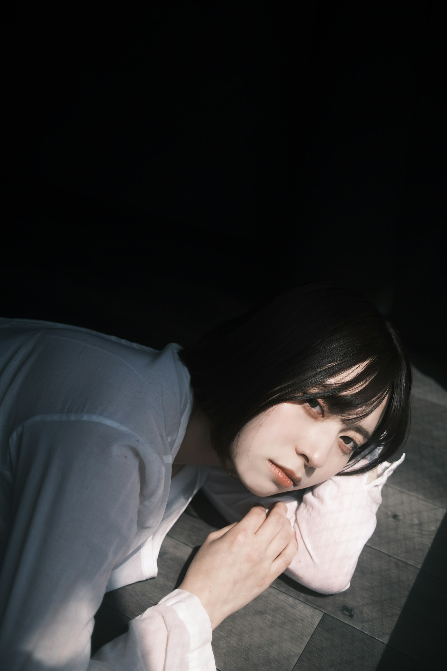 暗い背景に横たわる女性のポートレート 白い服を着ている しっとりとした表情