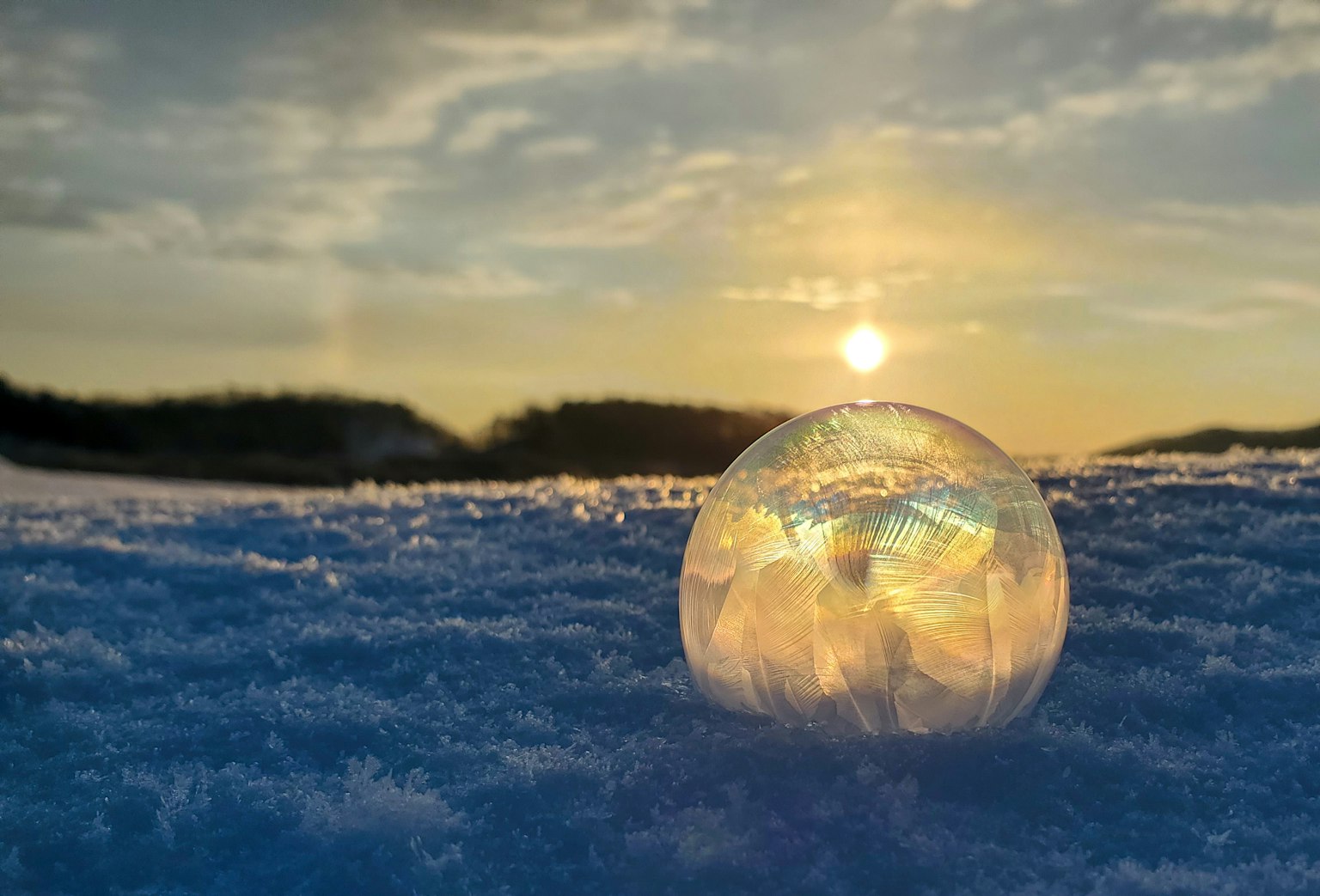 Eine schöne Szene einer Eiskugel auf Schnee, die den Sonnenuntergang reflektiert
