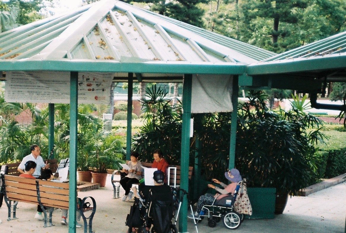 khu vực nghỉ ngơi có mái che trong vườn xanh với ghế dài và mọi người