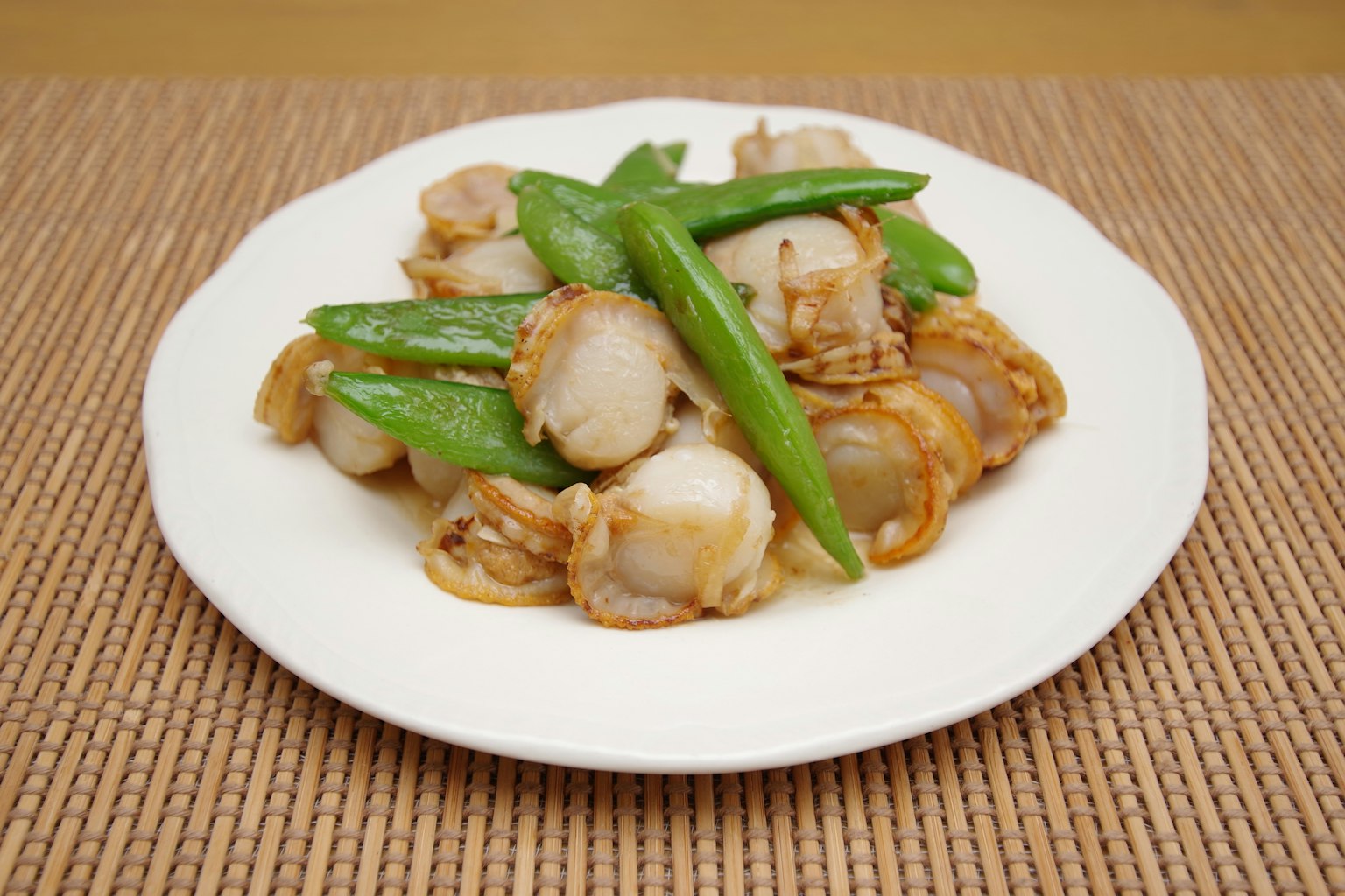 Hidangan kerang dan kacang polong di piring putih