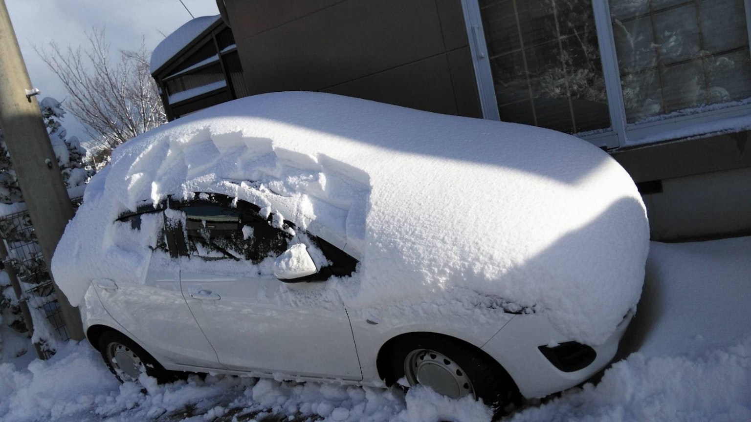 Voiture recouverte de neige épaisse avec un paysage enneigé autour