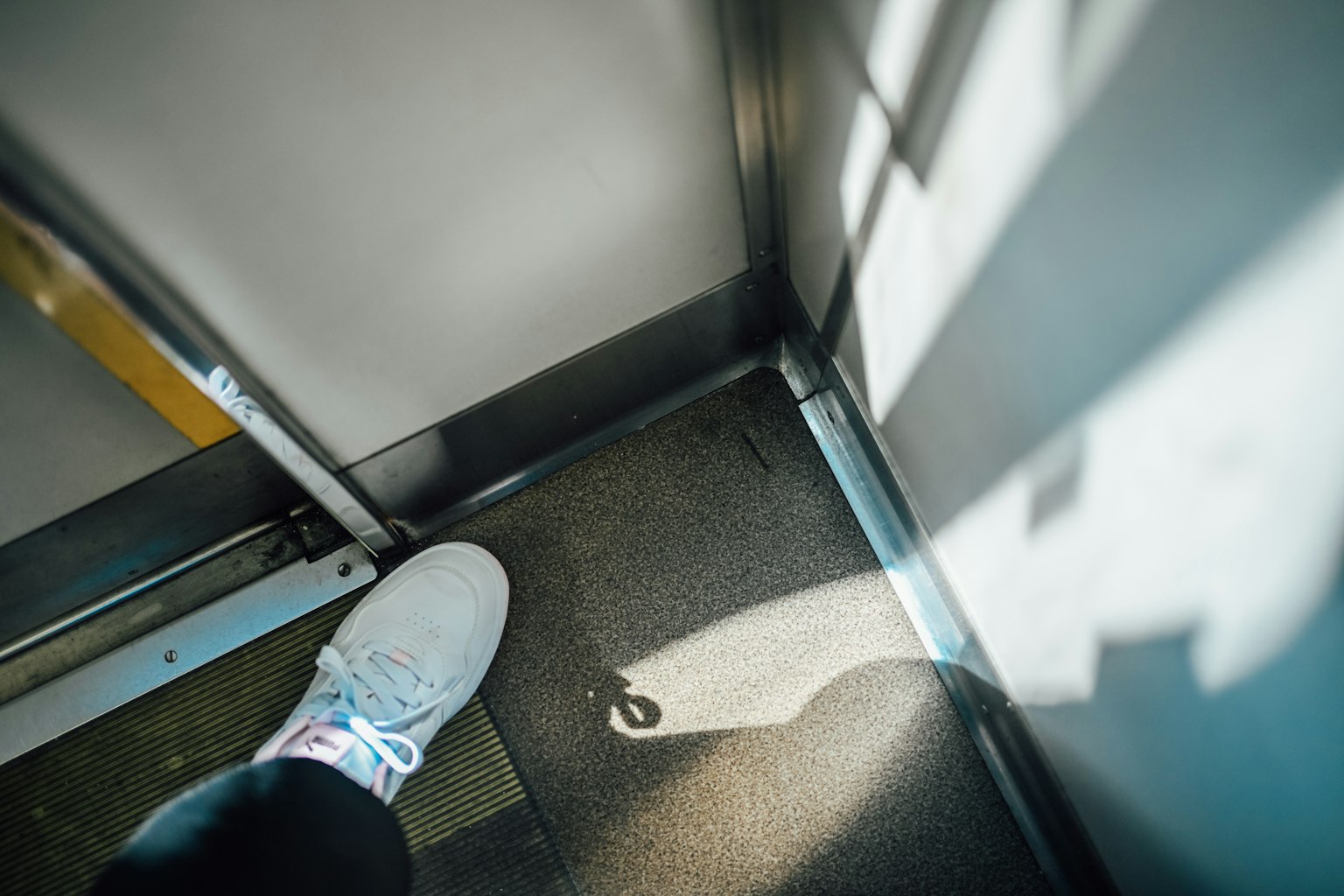 Fuß in einem Aufzug, der einen Schatten auf den Boden wirft