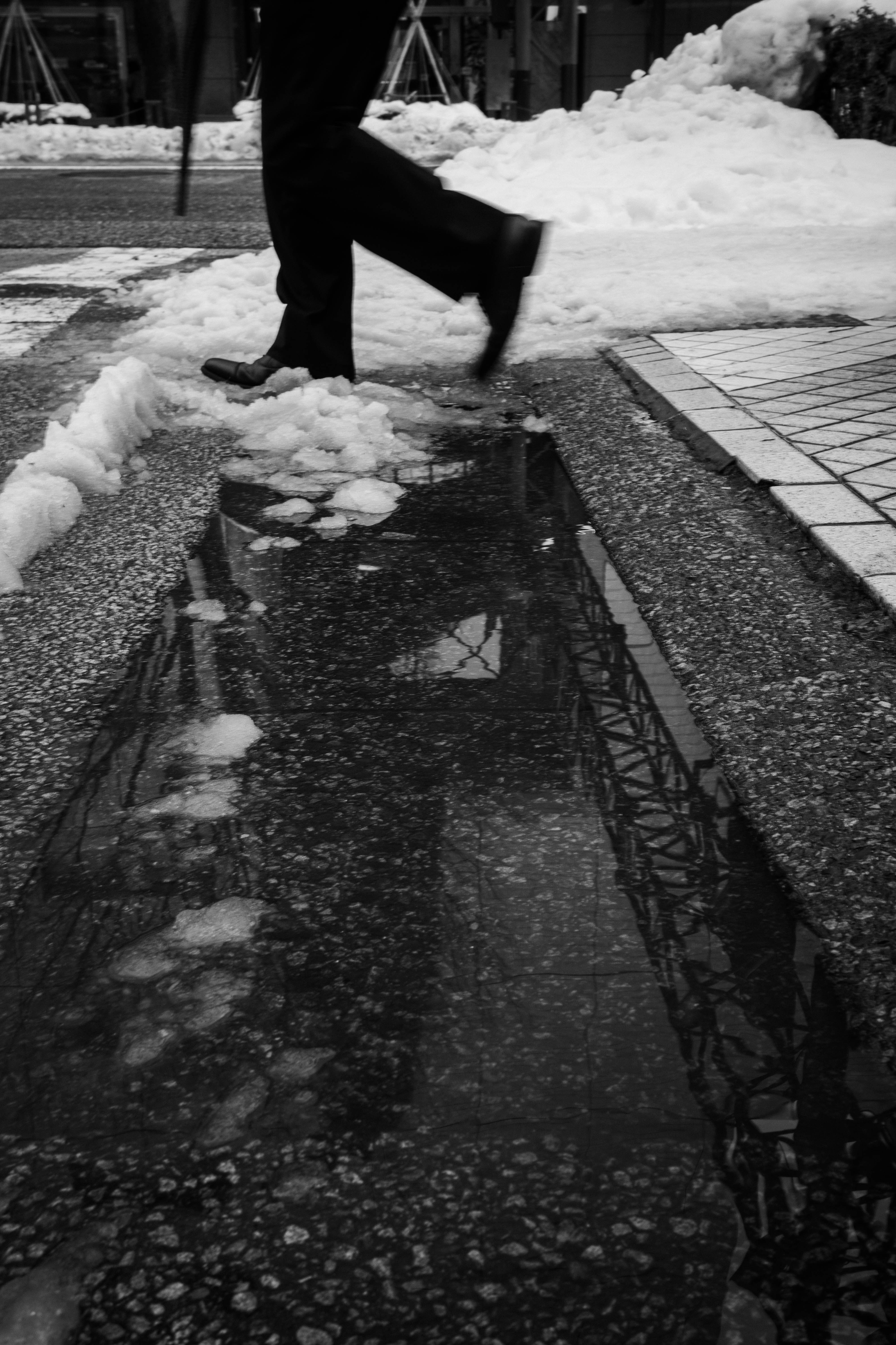 雪の歩道で雪かきをする人の手前姿