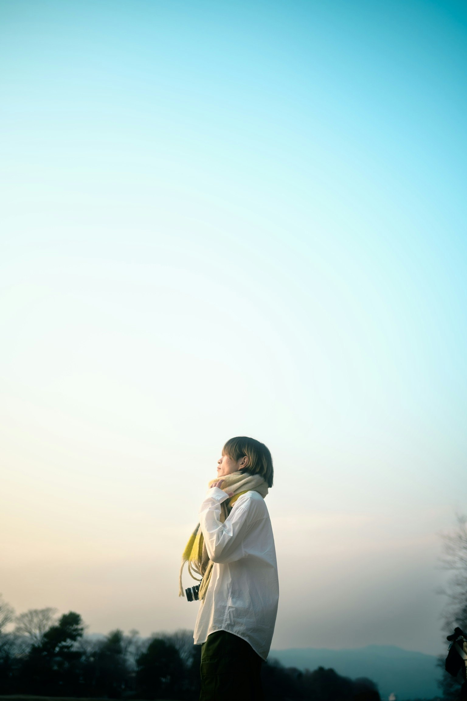 夕暮れの空を背景にしたコート姿の女性