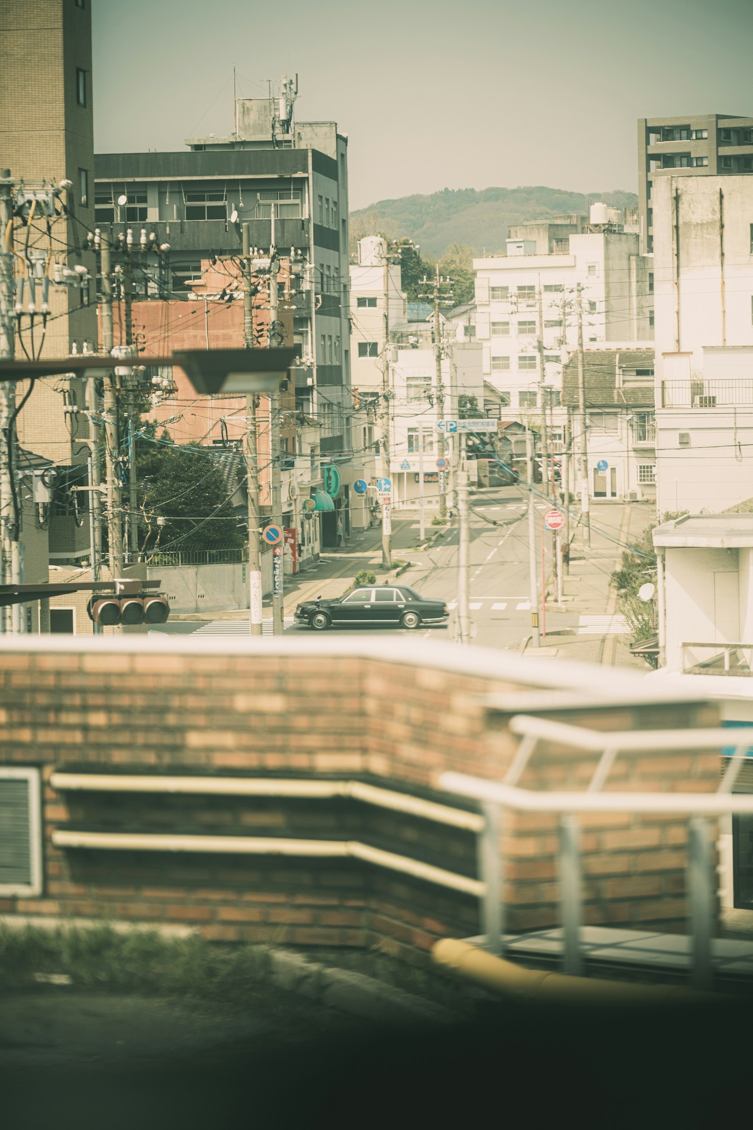 模糊的街道景觀，遠處有建築和山丘