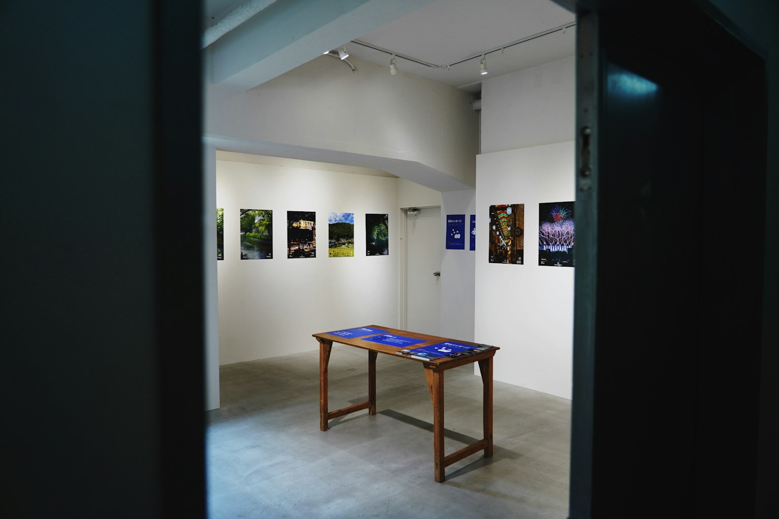 Interior de una galería de arte con fotografías en las paredes y una mesa de madera en el centro