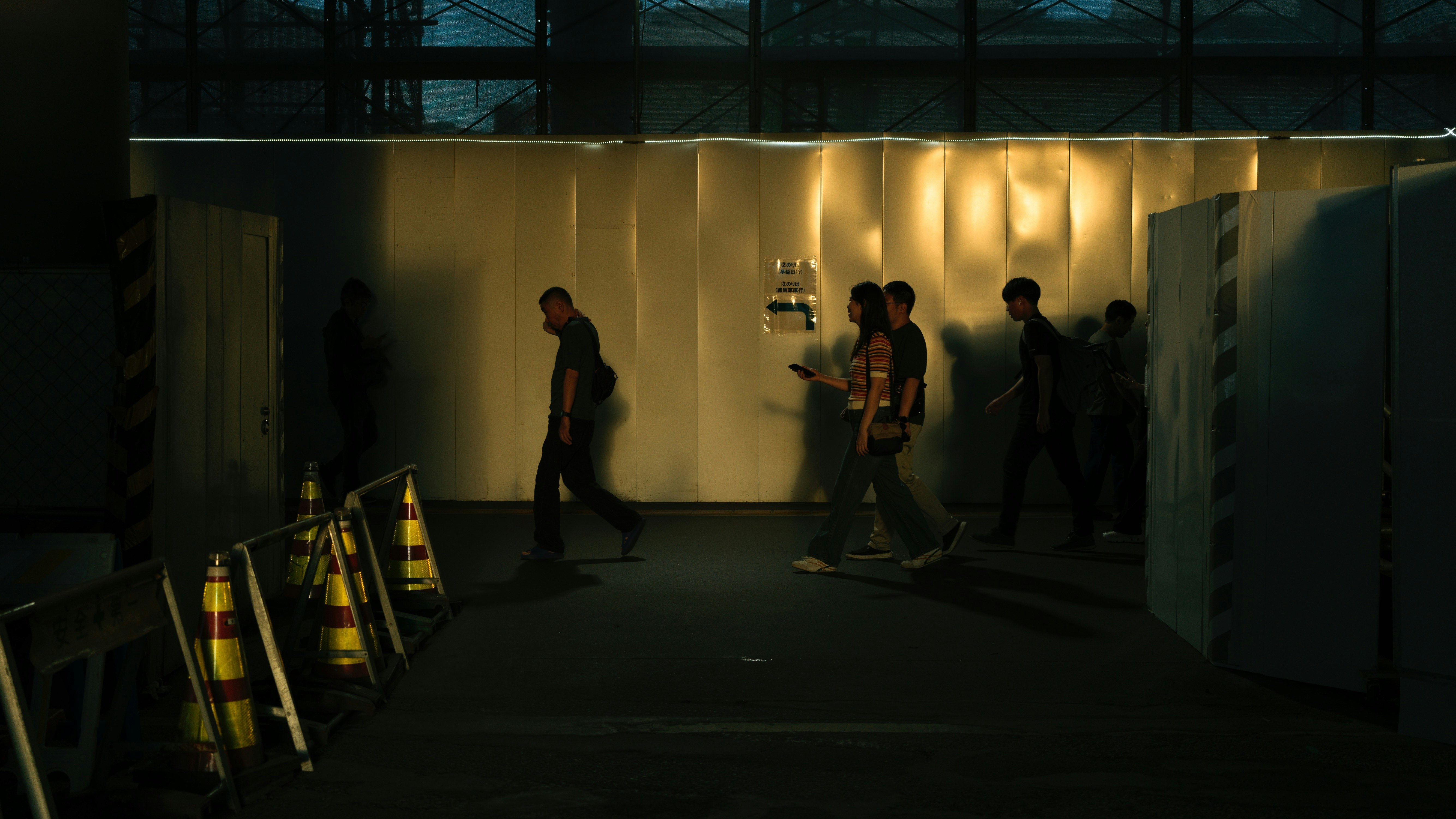 entrée d’une ruelle de nuit avec des personnes qui traversent un passage étroit